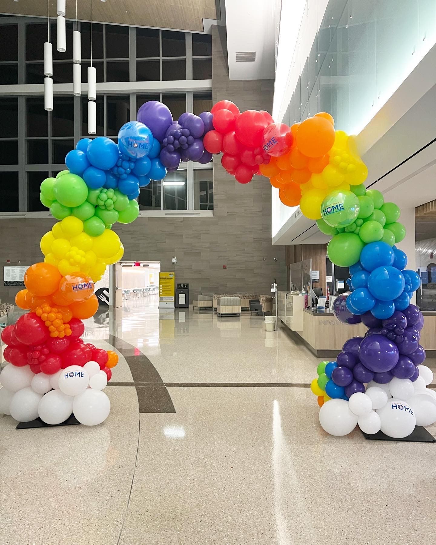 A rainbow colored balloon arch in a hallway