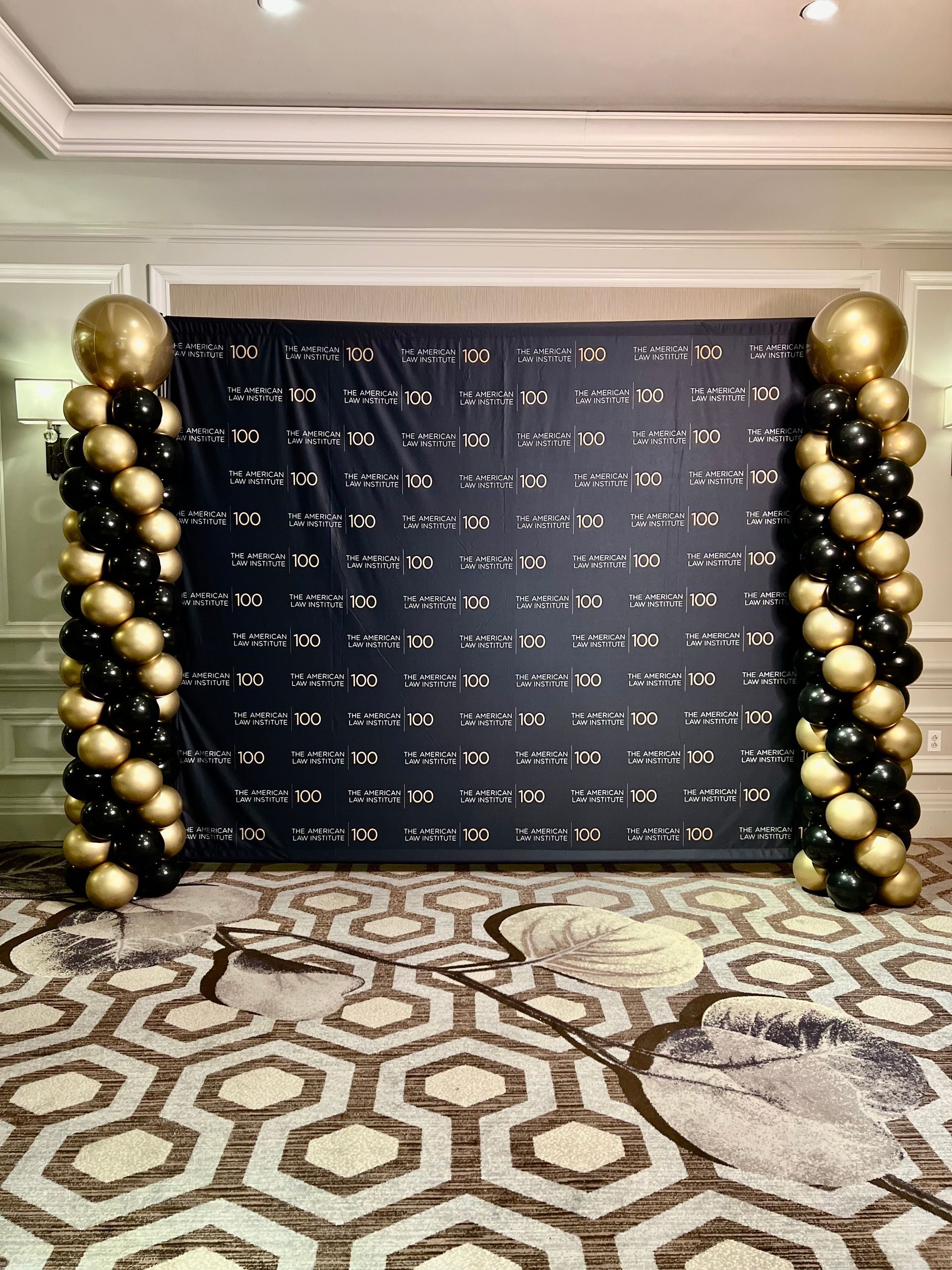 A room filled with balloons and a black and gold backdrop.