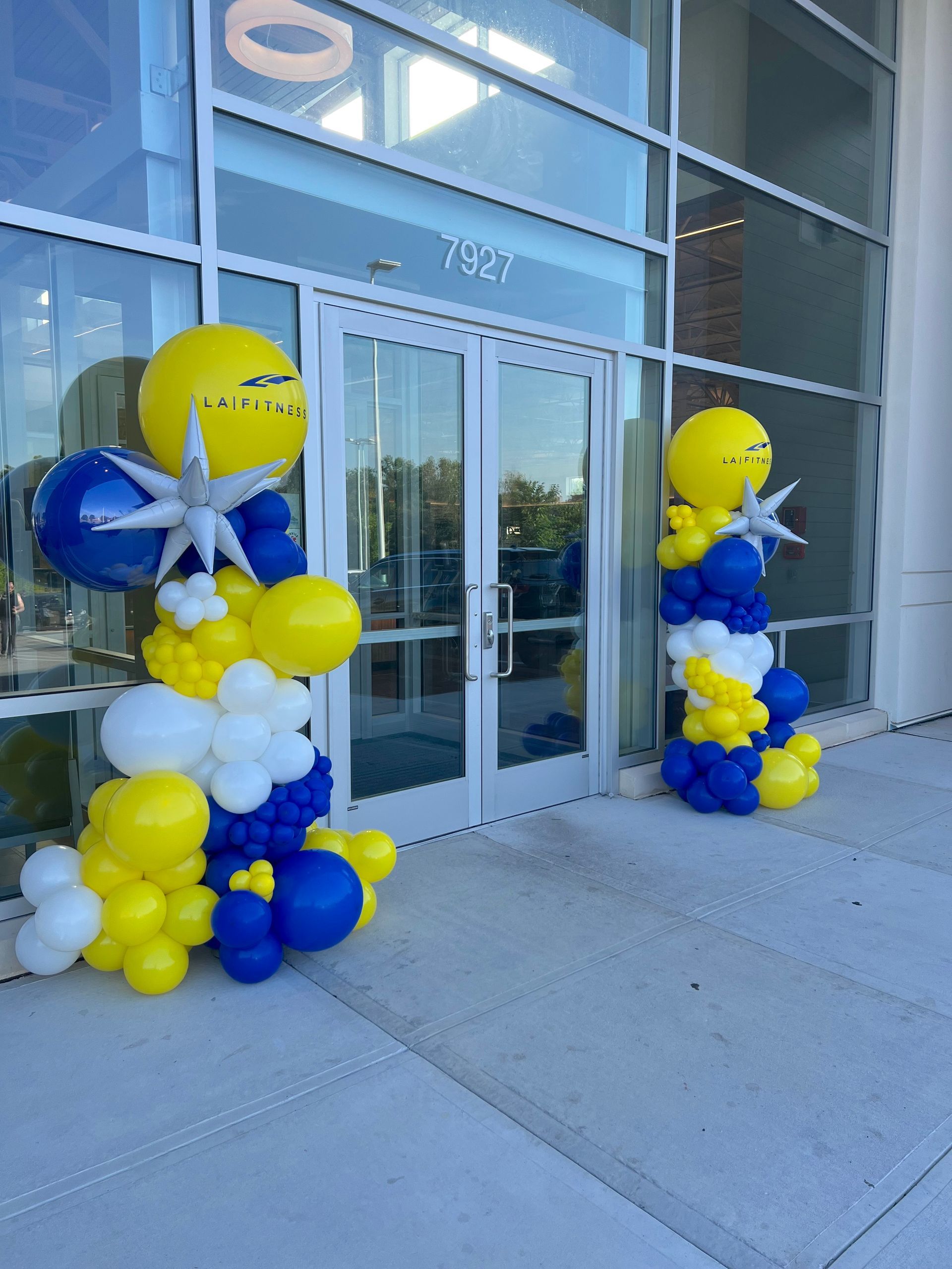 Blue and yellow balloons are lined up in front of a building