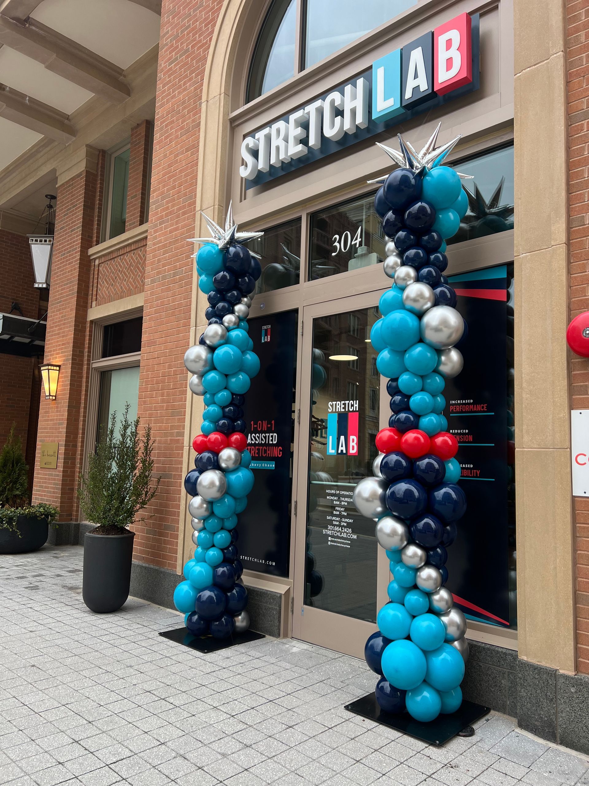 A stretch lab store is decorated with blue , red , and silver balloons.