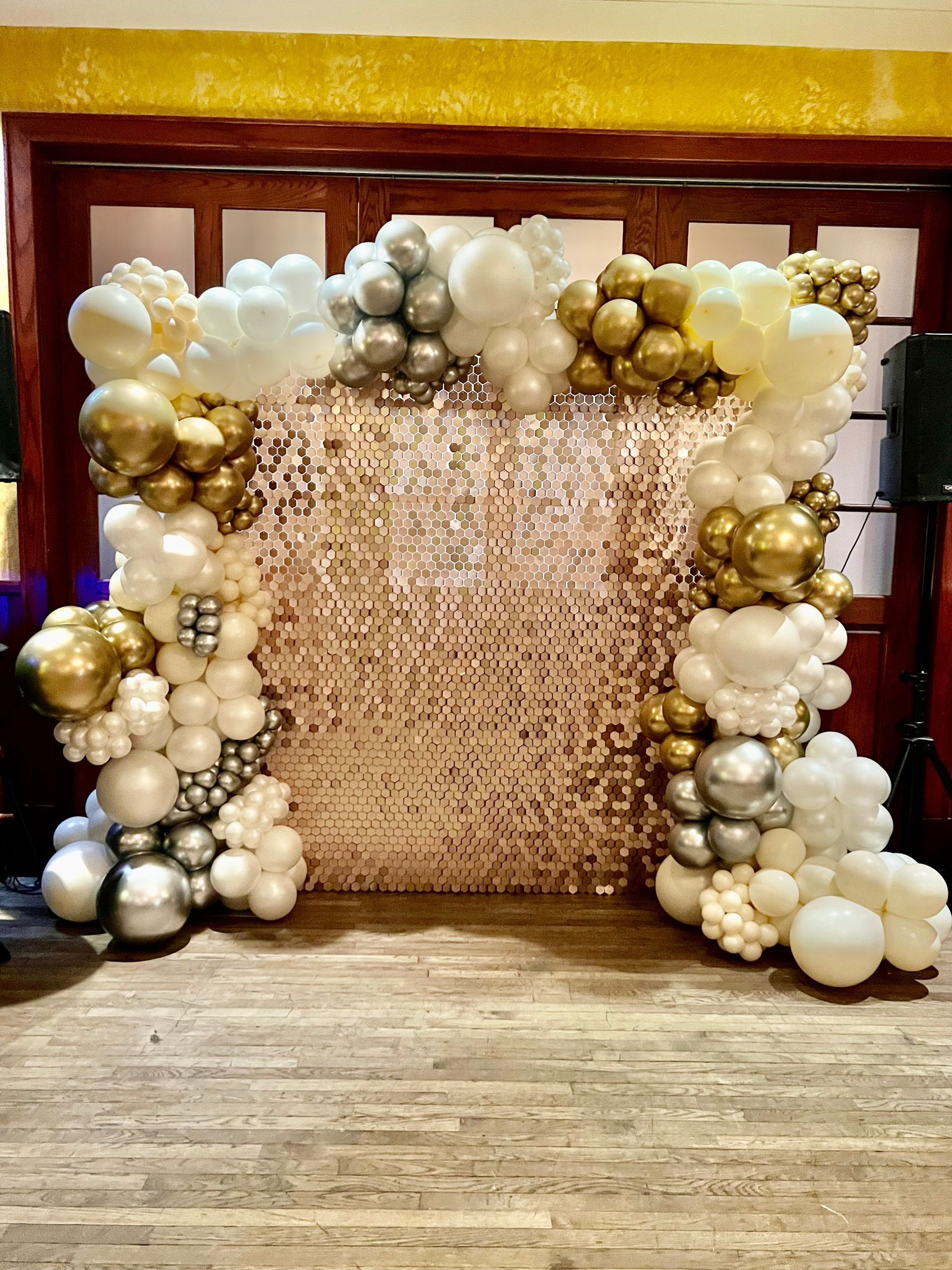 A room filled with balloons and sequins on a wooden floor.