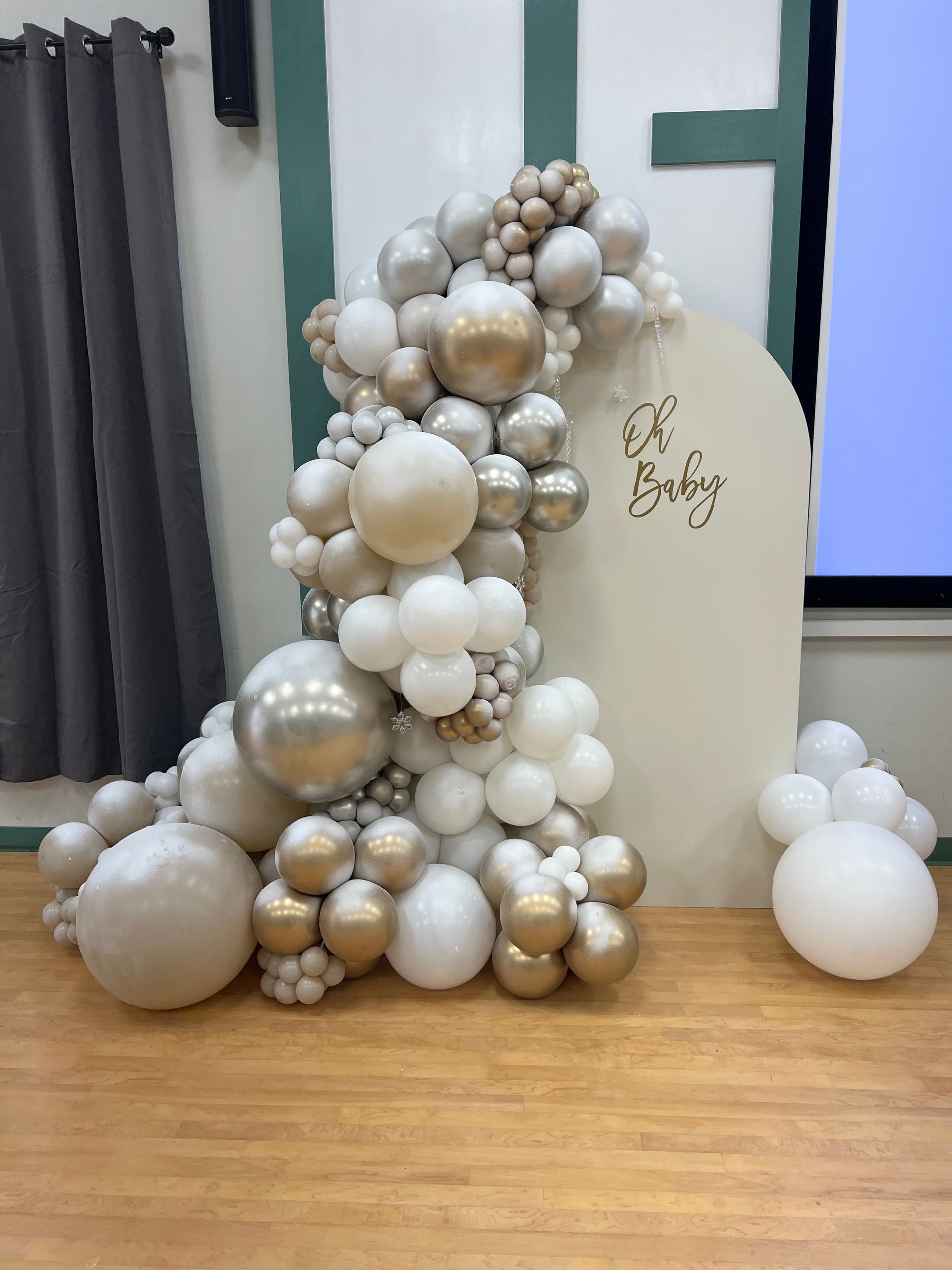 A bunch of balloons are sitting on a wooden floor in a room.