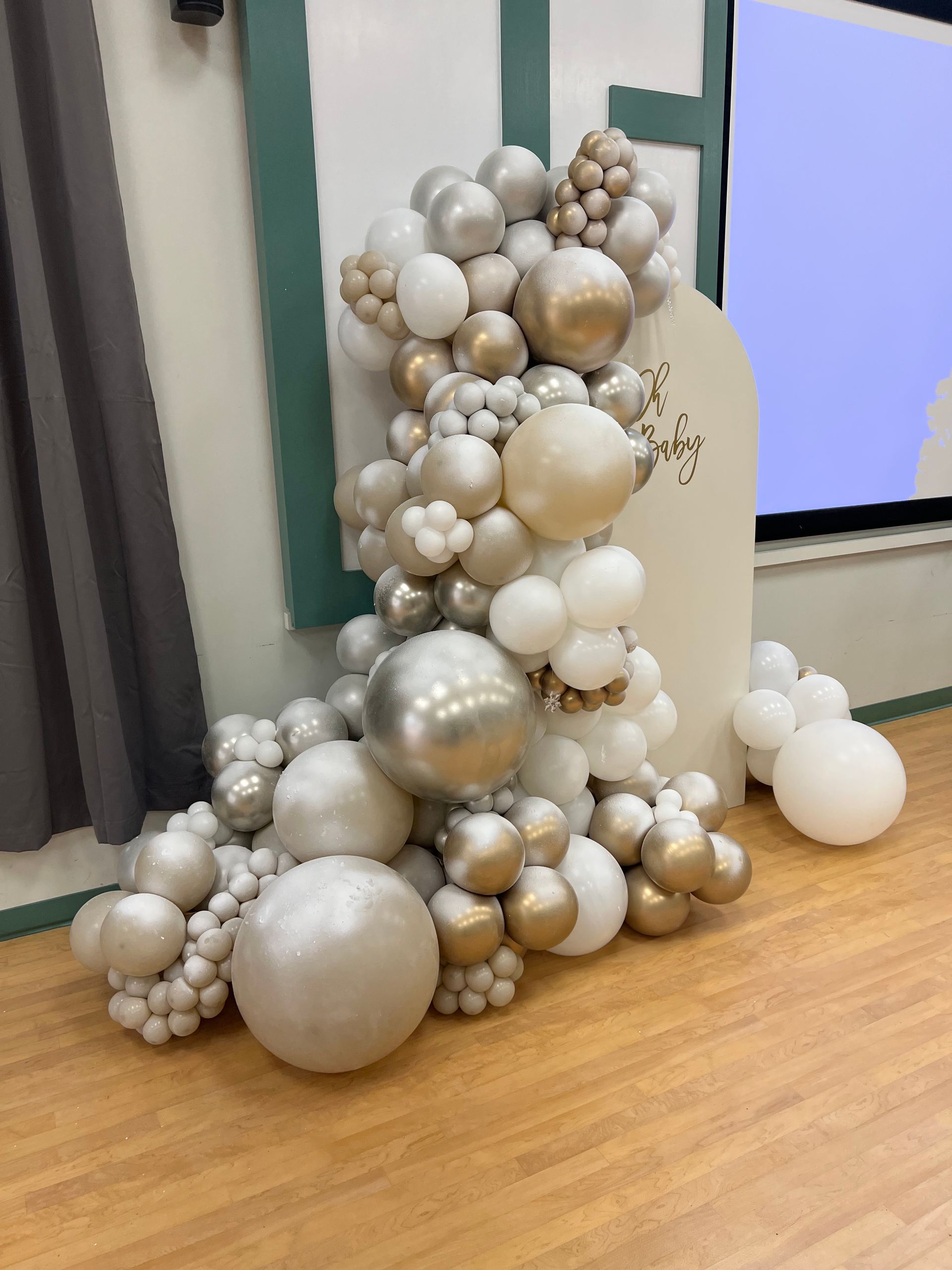 A bunch of balloons are sitting on a wooden floor in a room.