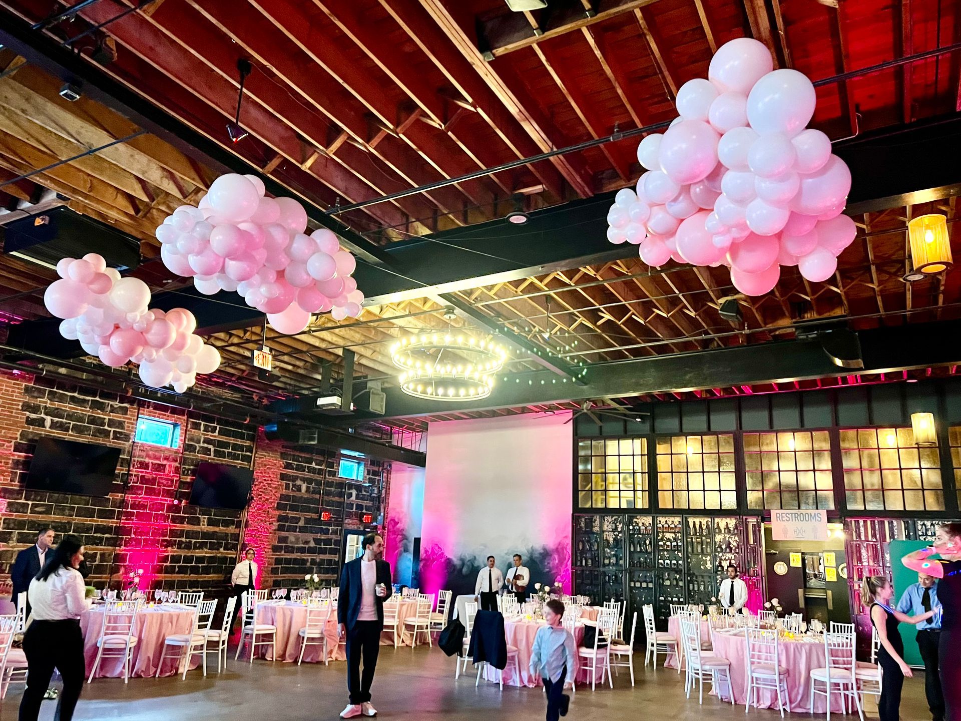 A large room with tables and chairs and balloons hanging from the ceiling.