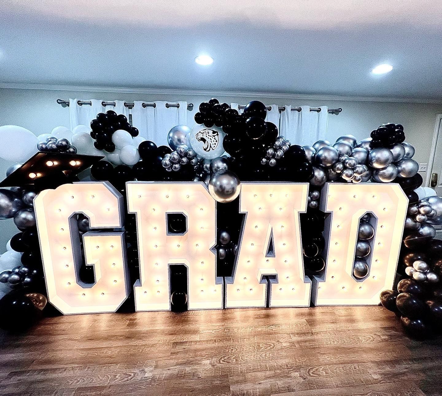 The word grad is surrounded by balloons and lights