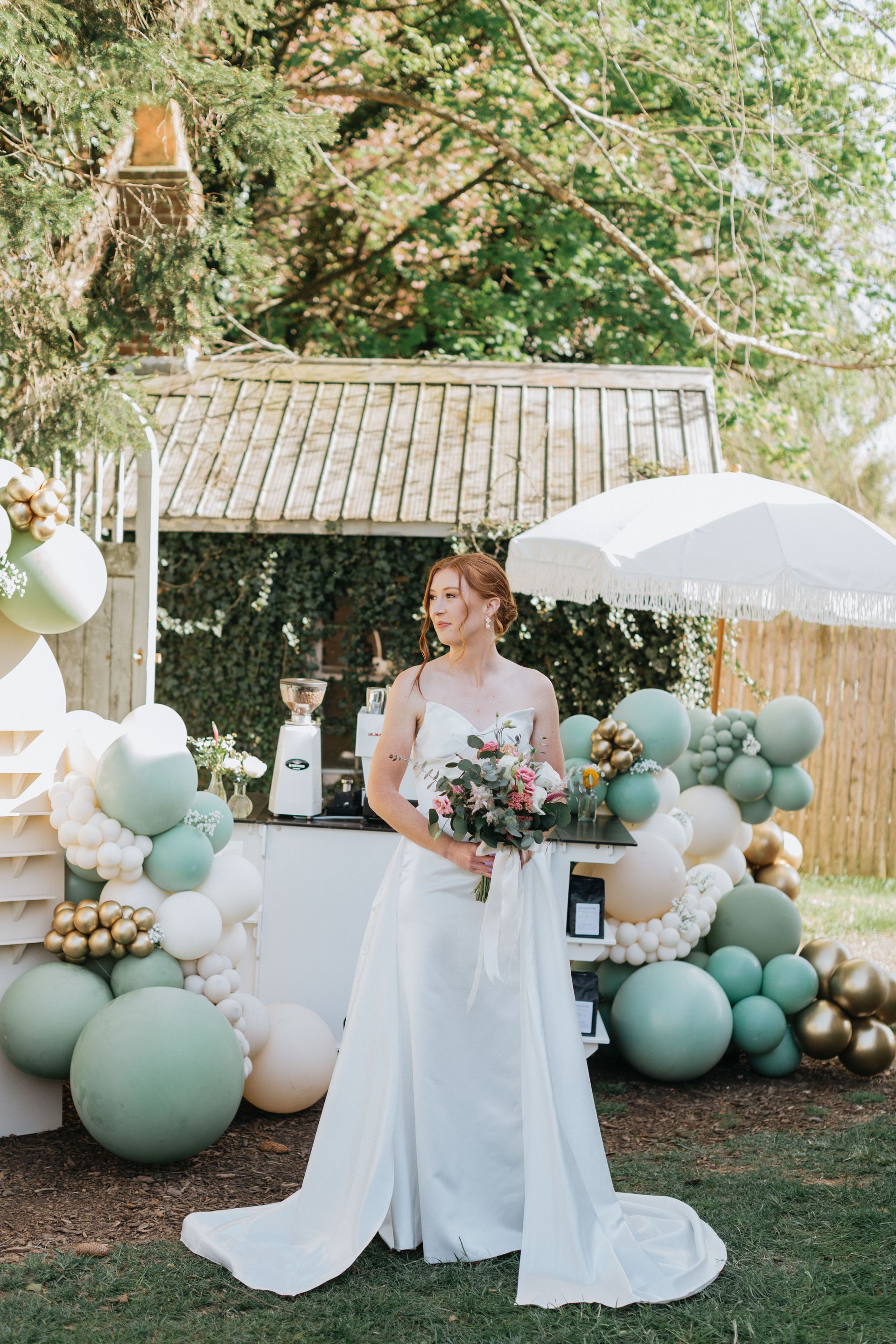 A bride in a wedding dress is standing in front of a bar decorated with balloons.