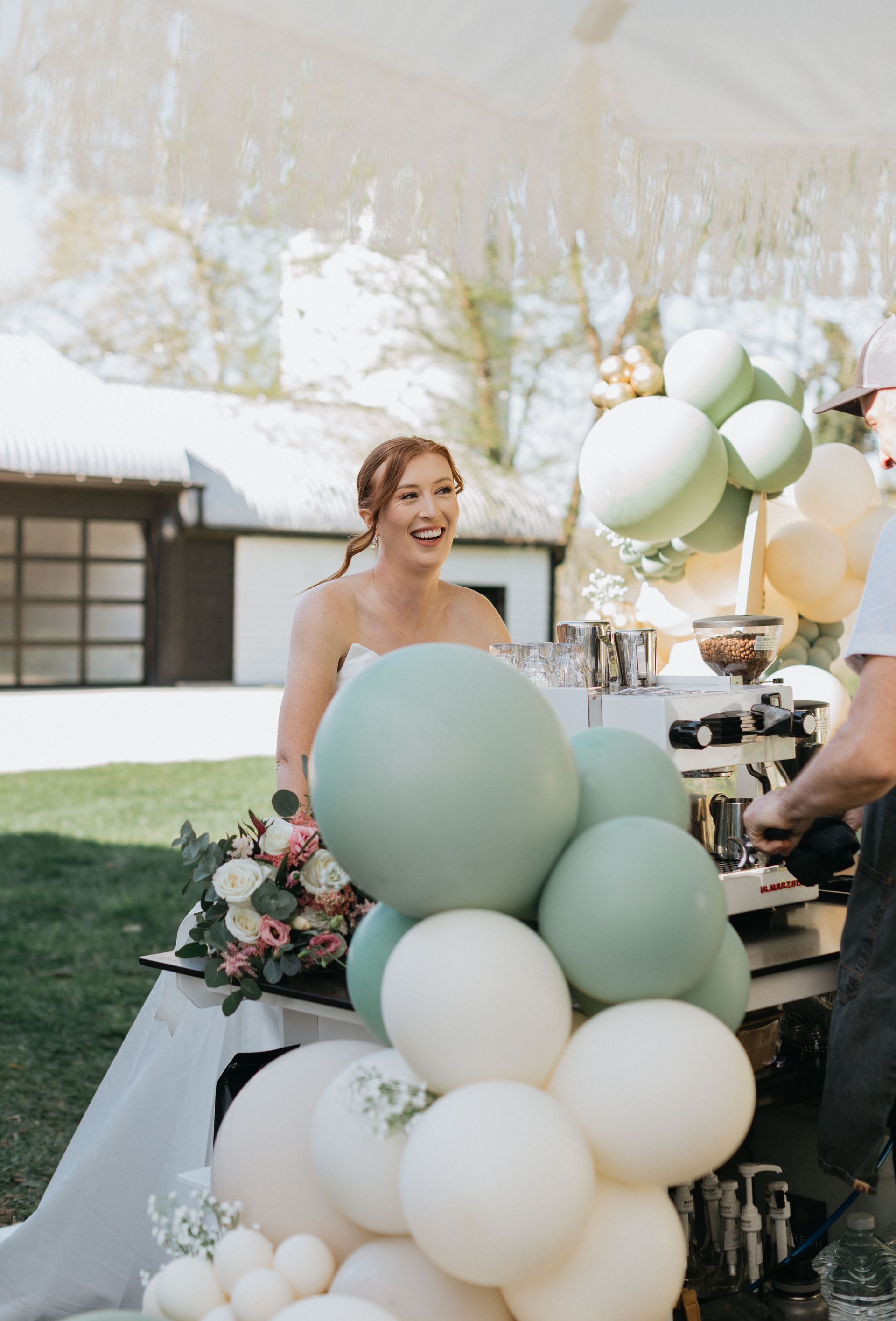 A bride is sitting at a table surrounded by balloons.