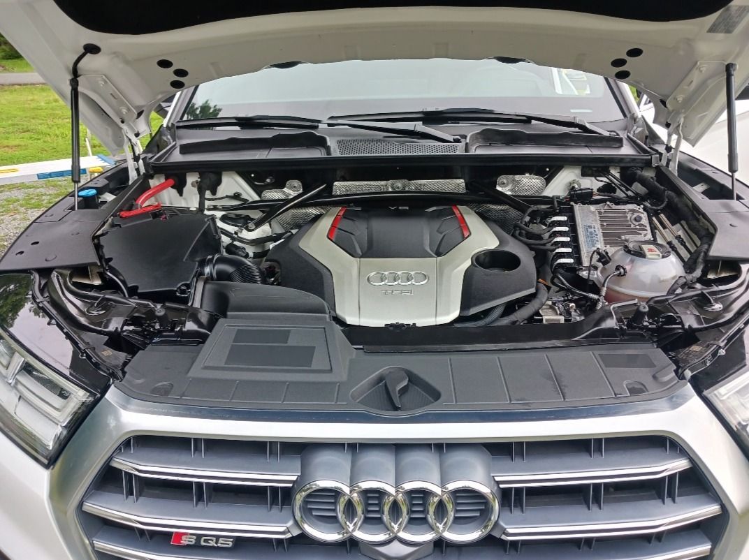Audi SQ5 SUV engine bay with hood open; silver, black, and red components.