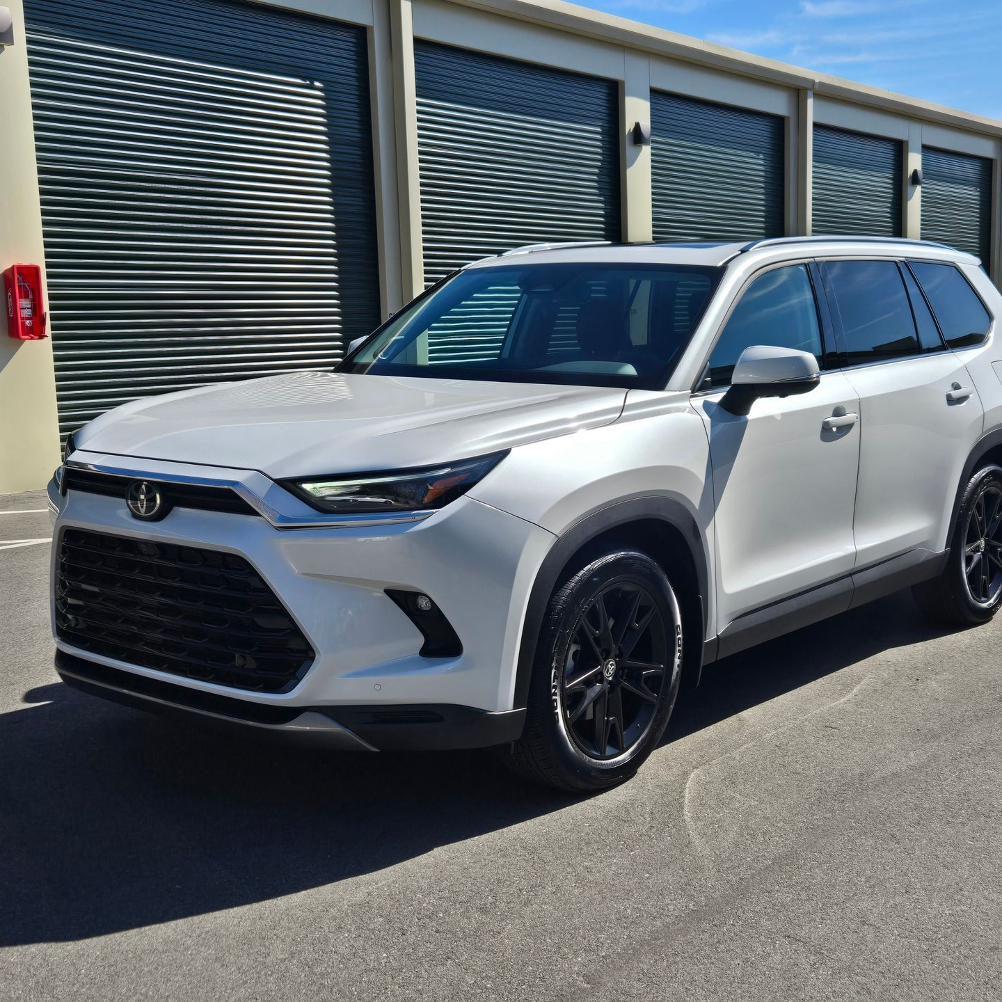 White Toyota SUV parked in front of storage units with black wheels and tinted windows.
