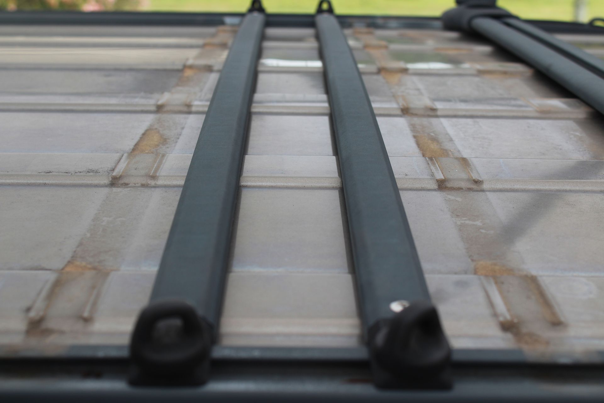 Two black roof rack crossbars on a vehicle roof, viewed from a low angle.