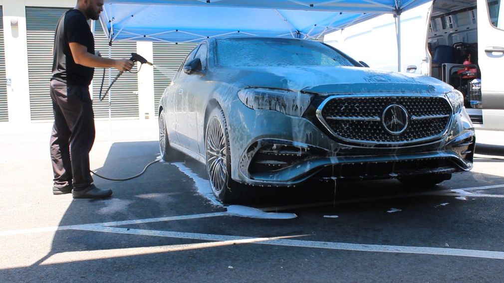 Person cleaning a black car rim with a cloth, wearing a respirator and gloves.