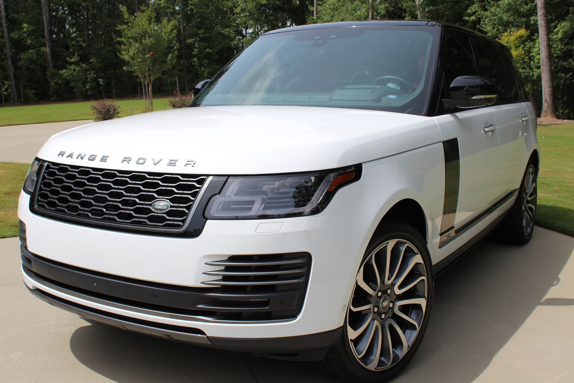 White Range Rover SUV parked in a driveway with black roof, black grill, and silver wheels.