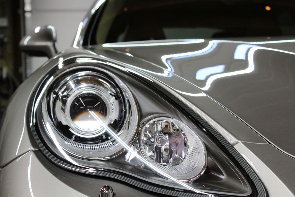 Close-up of a silver car headlight, showing the front, with detailed lights.