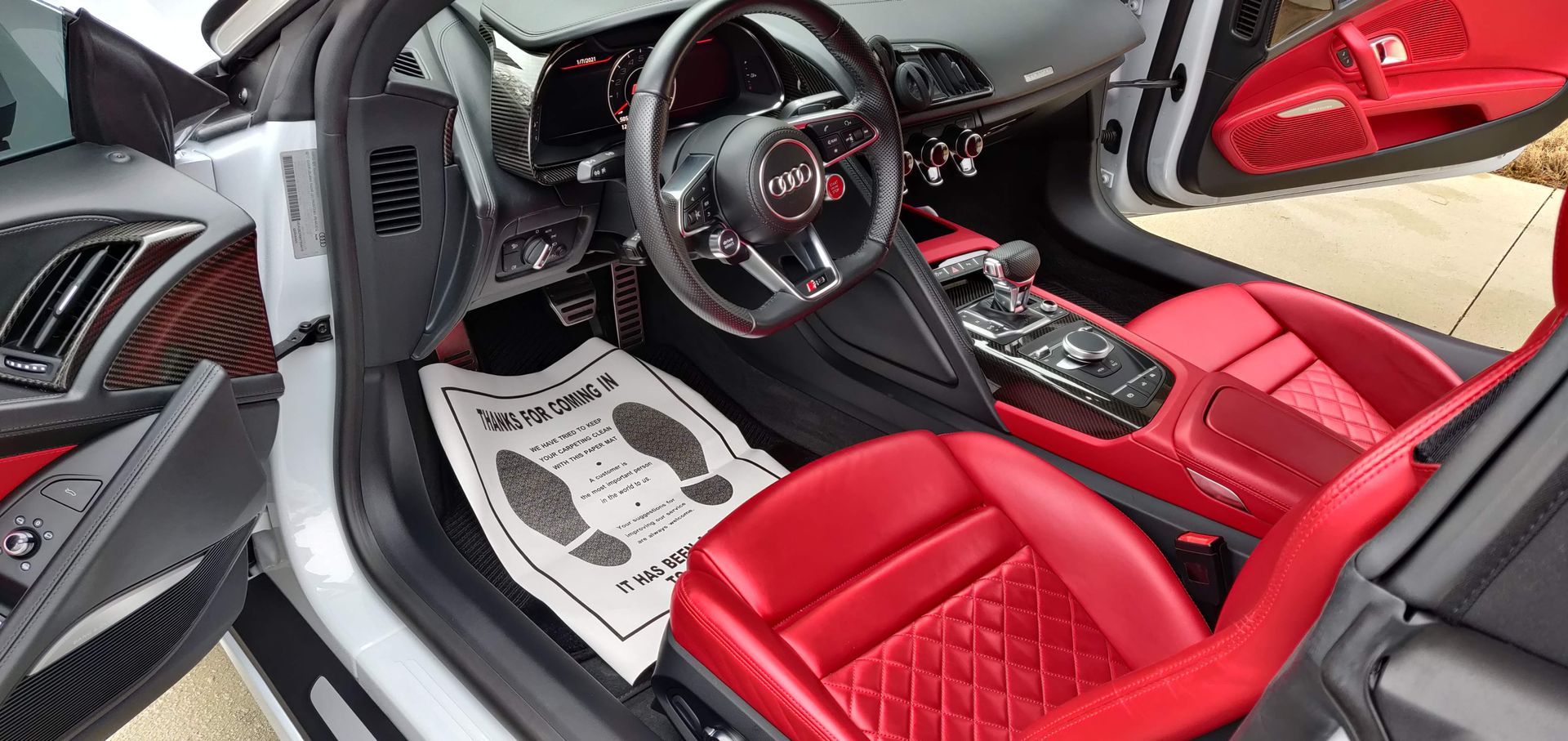 Interior view of a red leather Audi sports car with a black and silver dashboard, foot protection paper.