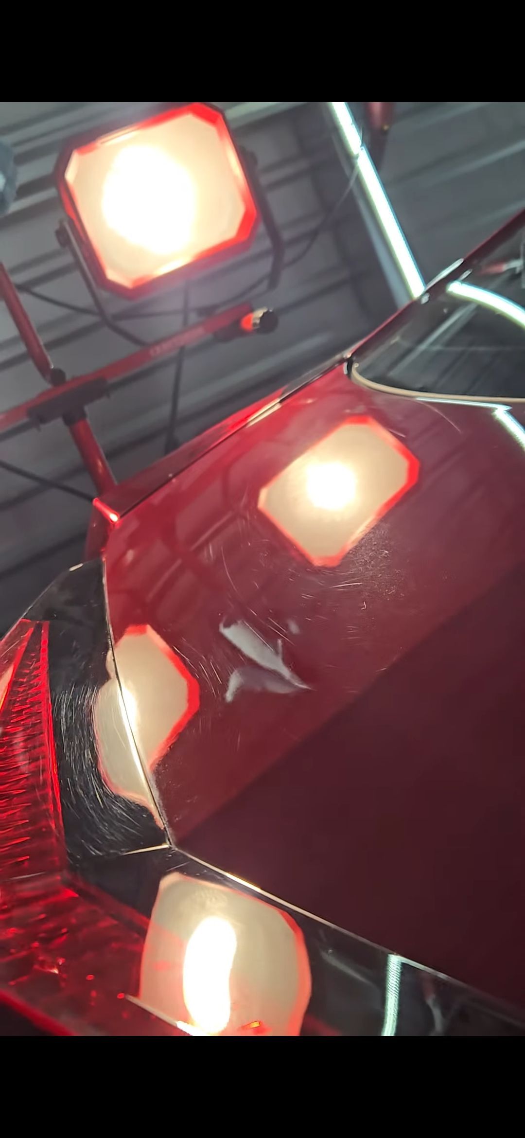 Red car in a garage, reflecting bright lights.