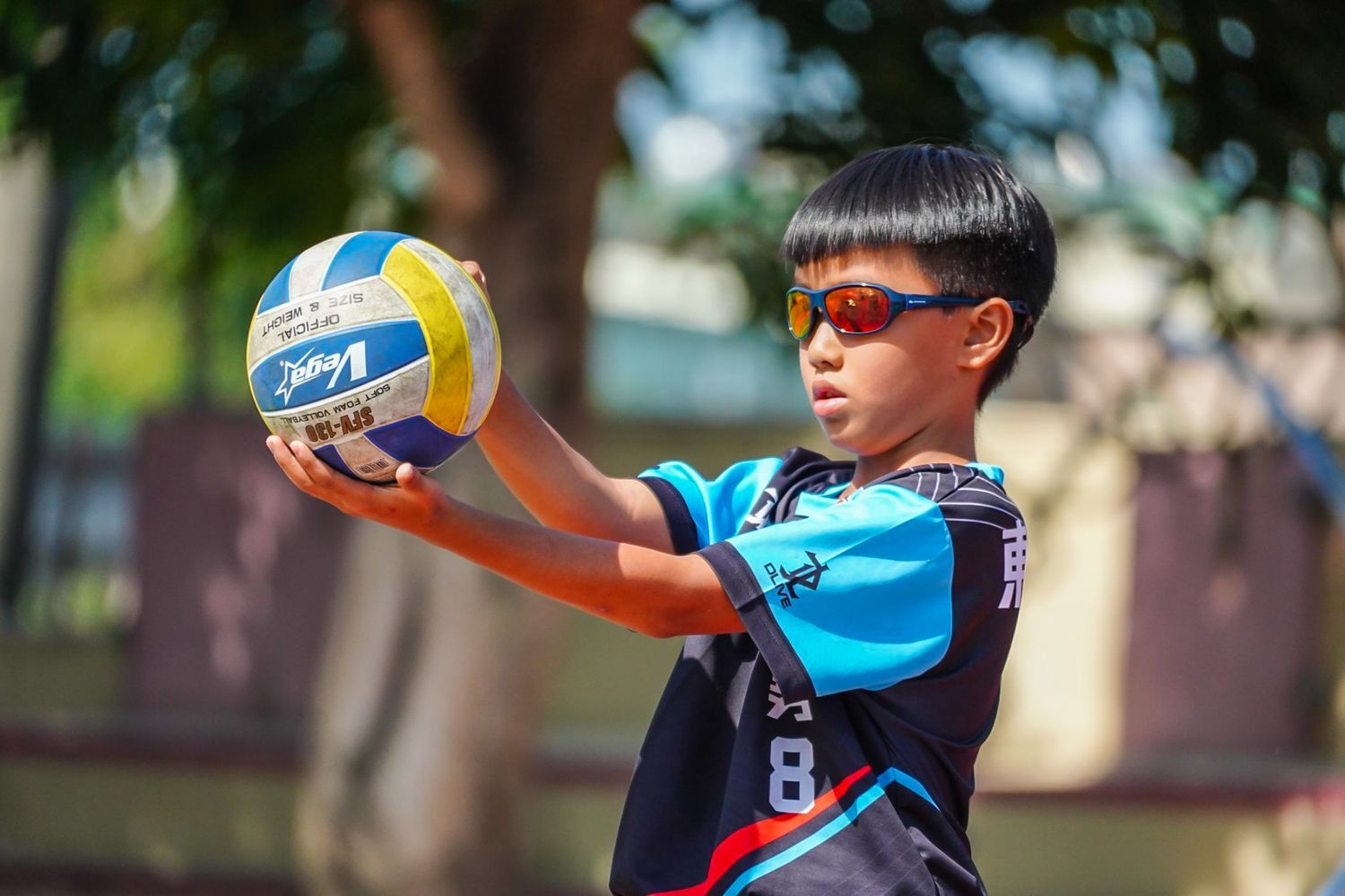 一個戴著墨鏡的小男孩手裡拿著一個排球。