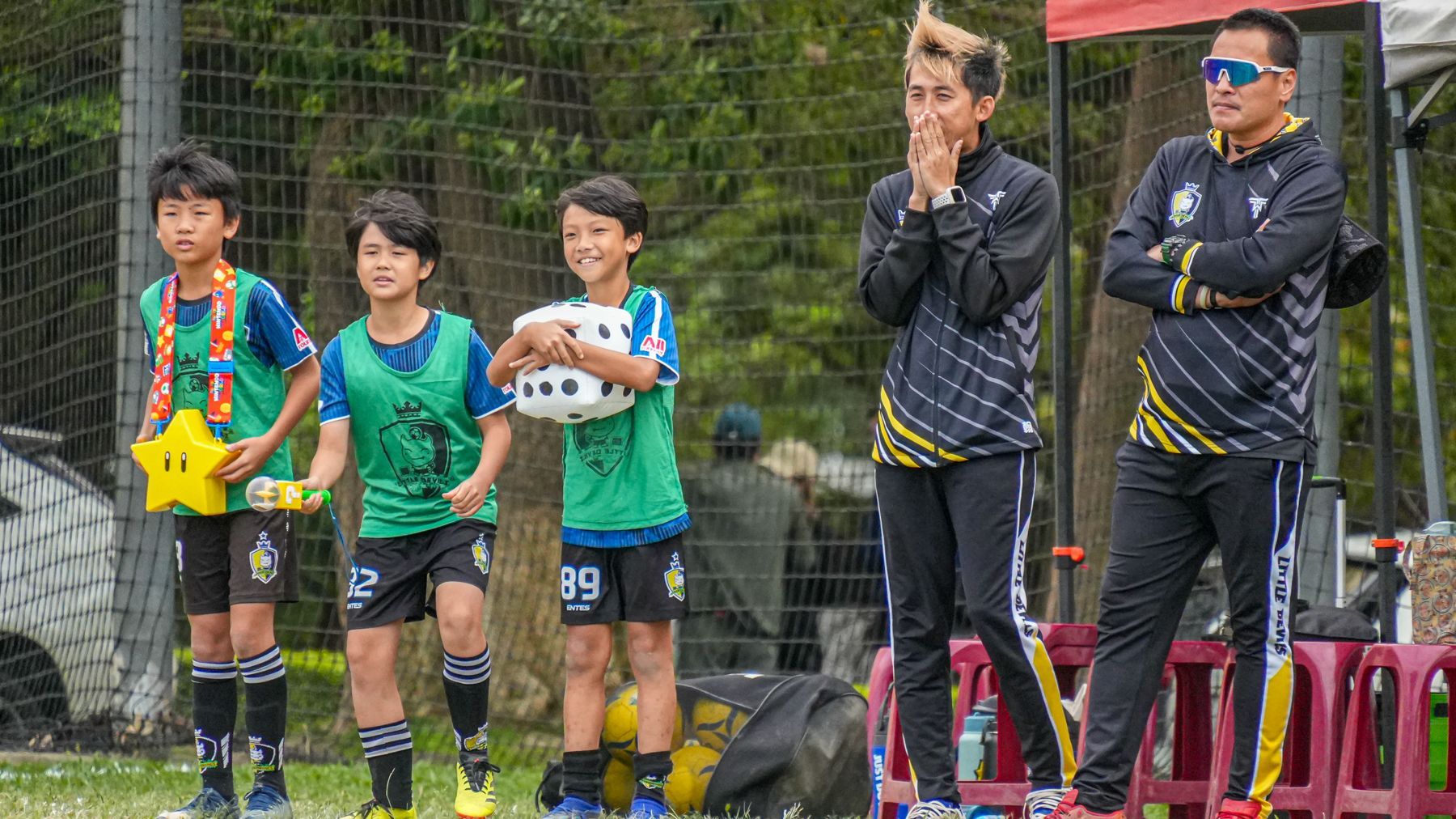 一群小男孩和他們的教練一起站在足球場上。