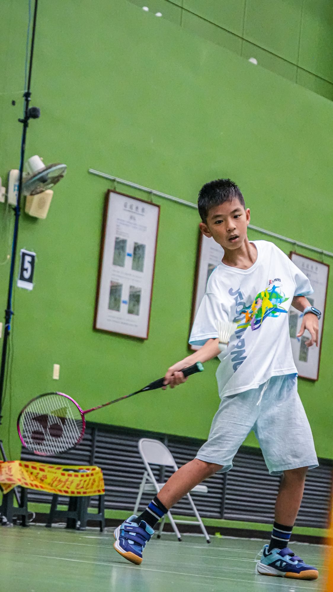 一個小男孩正在球場上打羽球。