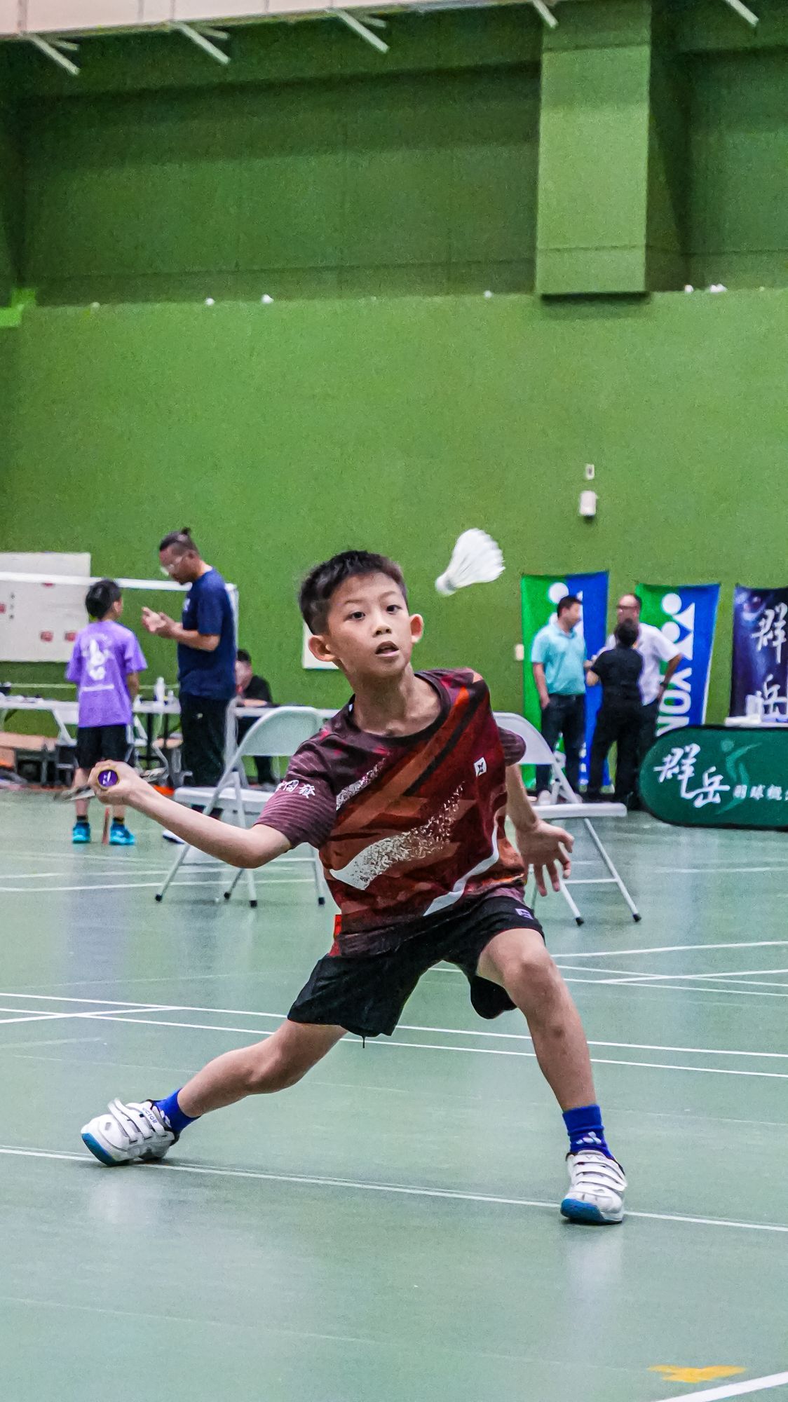 一個小男孩正在球場上打羽球。