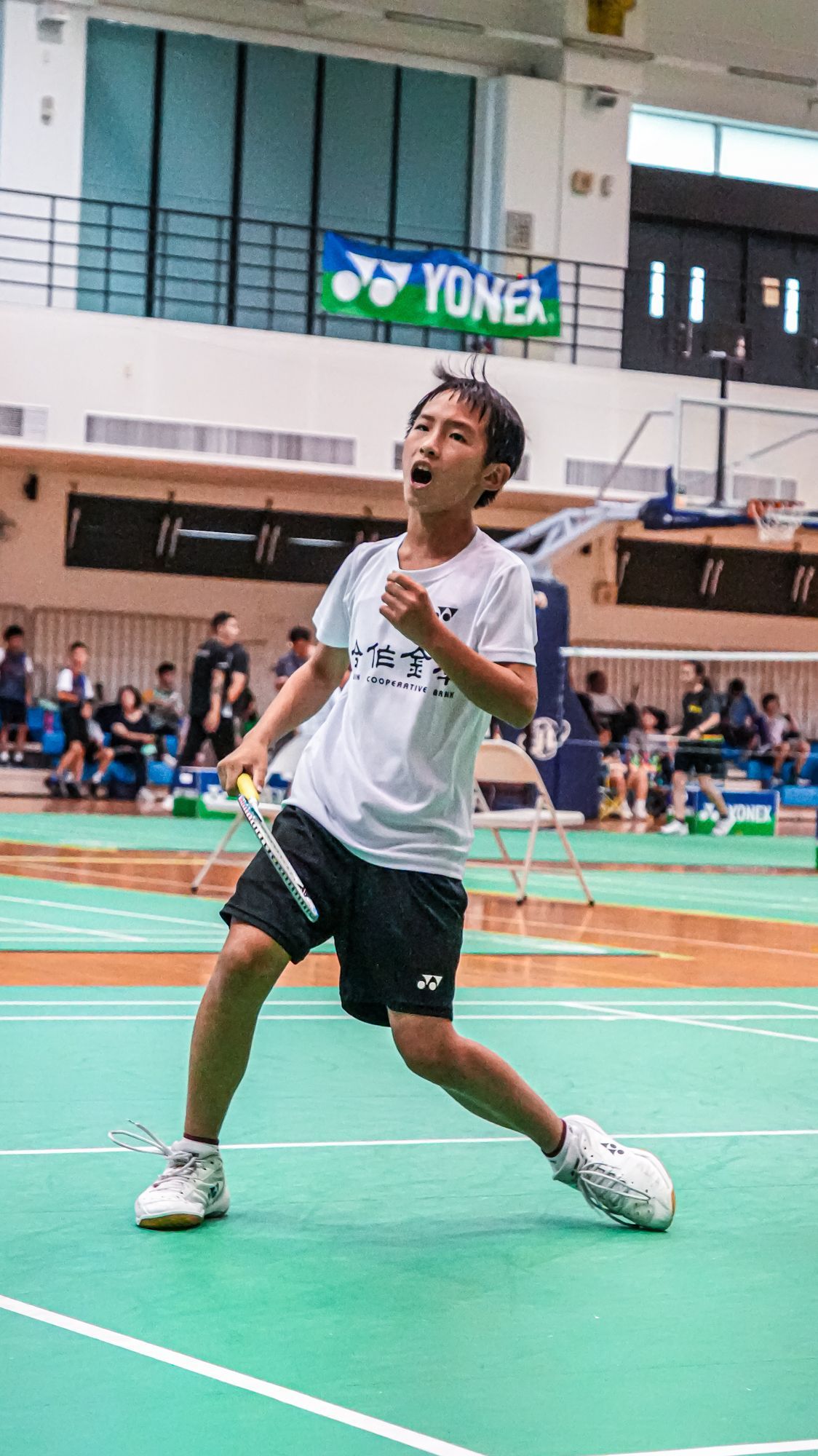 一個小男孩正在綠色的球場上打羽球。