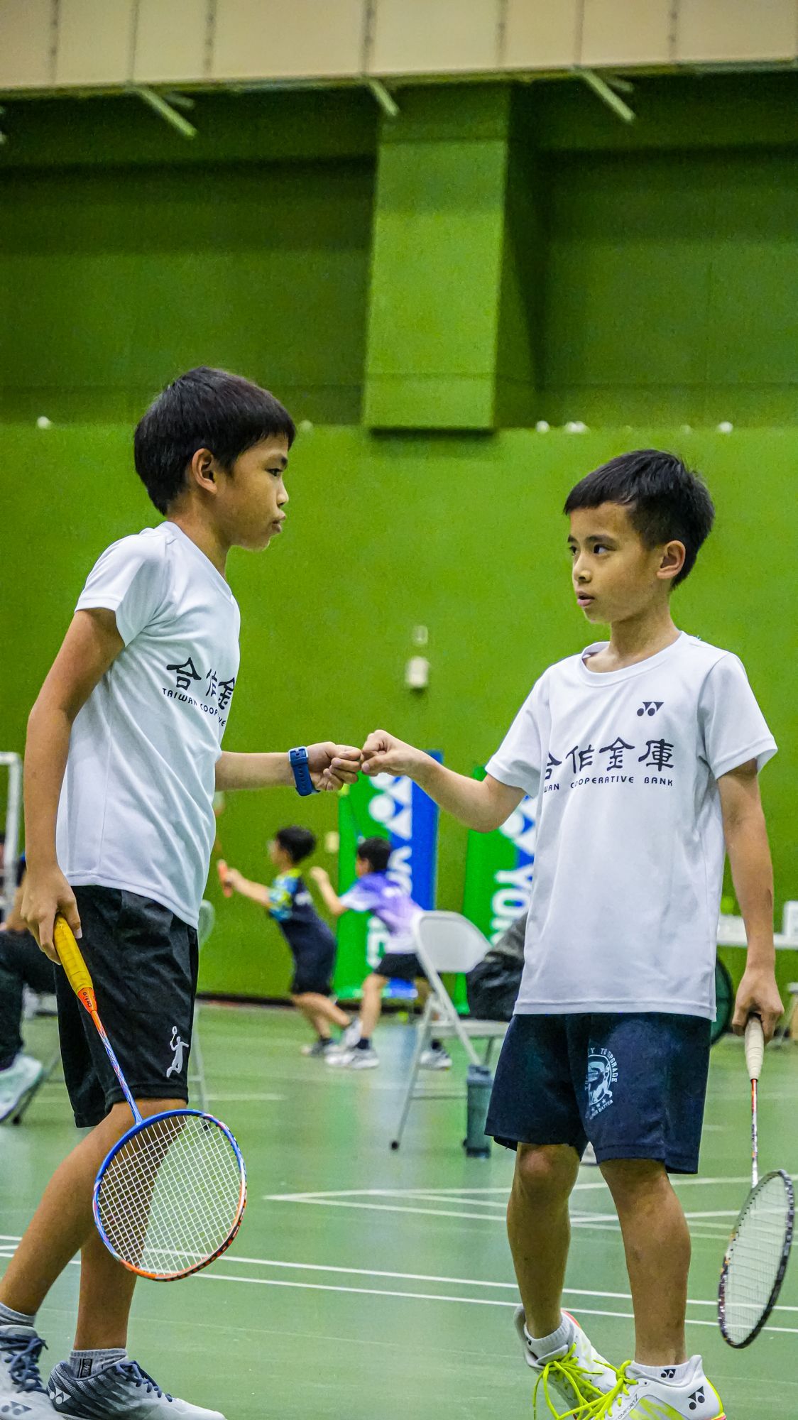 兩個小男孩在羽球場上握手。