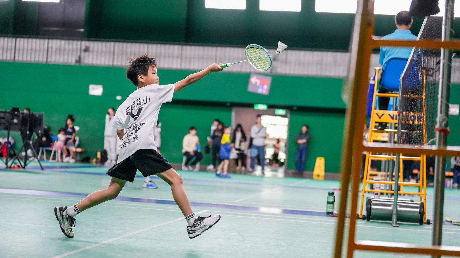 一個小男孩正在健身房打羽毛球。