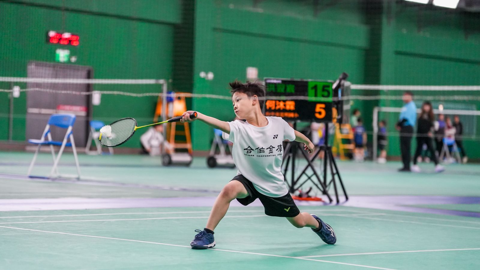 一個小男孩正在健身房打羽毛球。