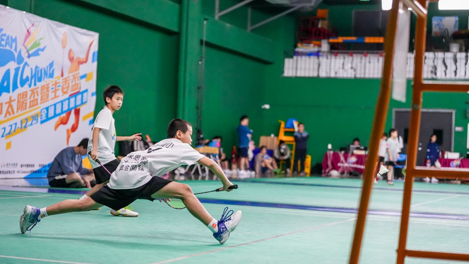 一群小男孩正在球場上打網球。