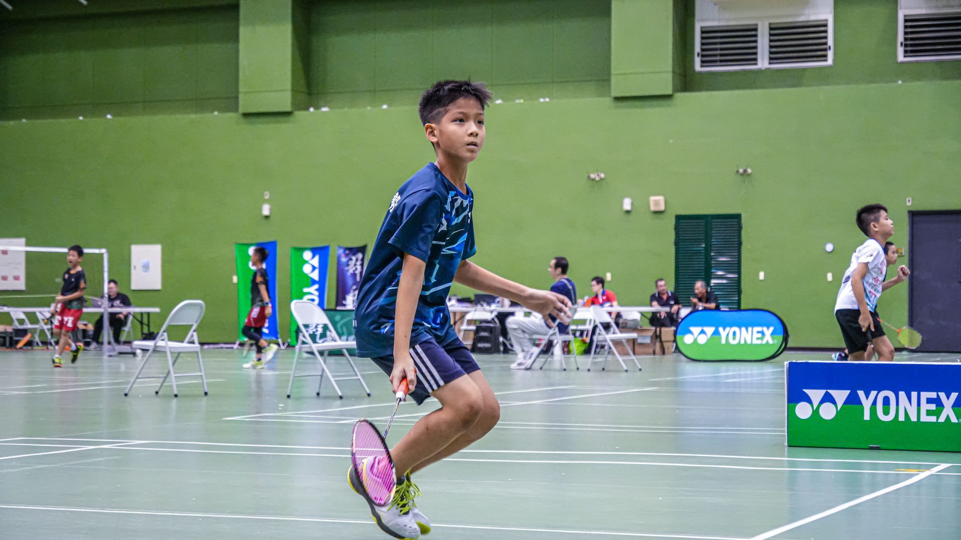 一個小男孩在球場上打羽球時在空中跳躍。