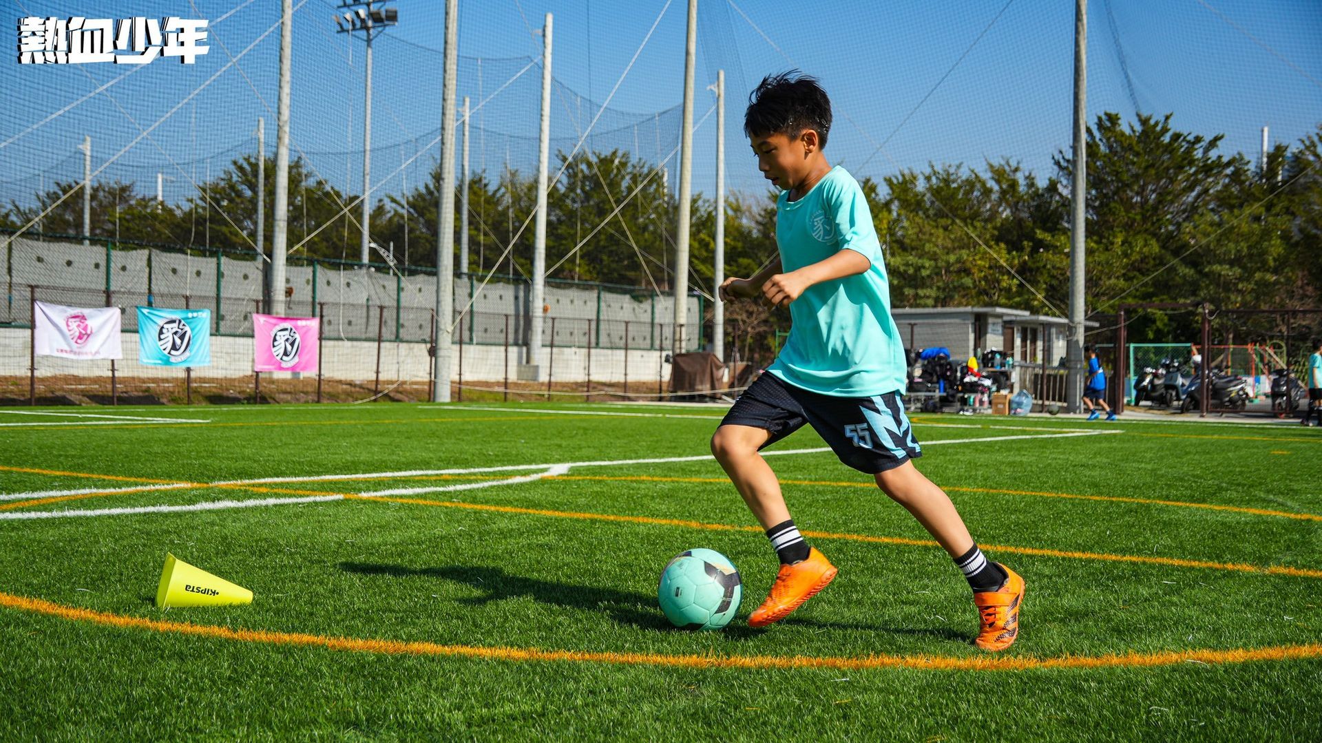 一個小男孩正在球場上踢足球。