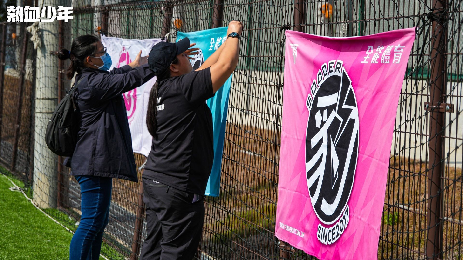 一個男人和一個女人正在柵欄上懸掛旗幟。