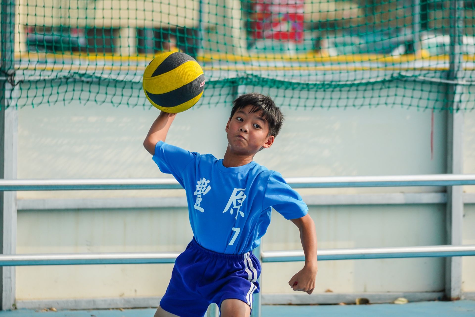 一個小男孩正在球場上打排球。