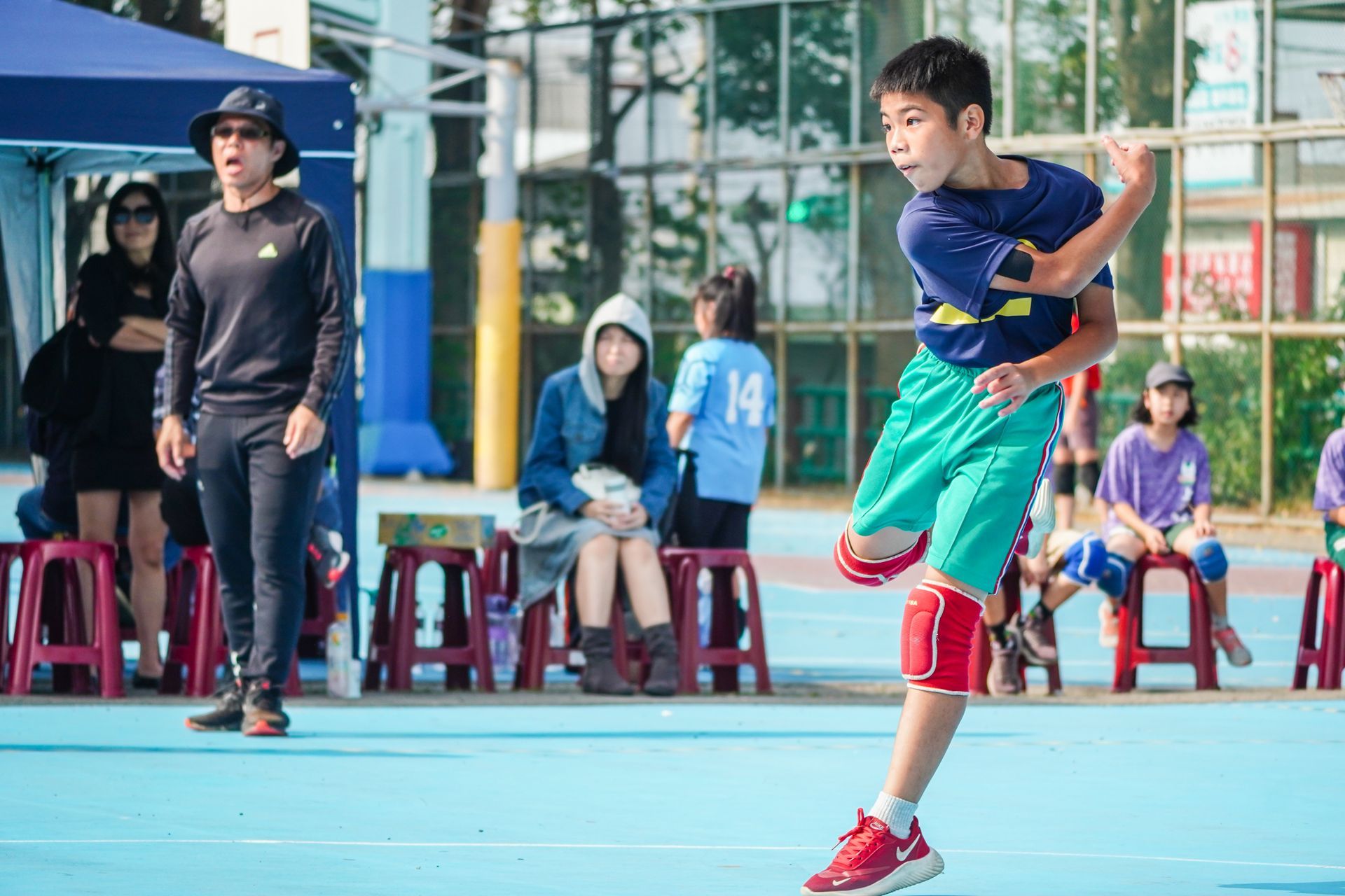 一個小男孩在球場上打籃球時在空中跳躍。