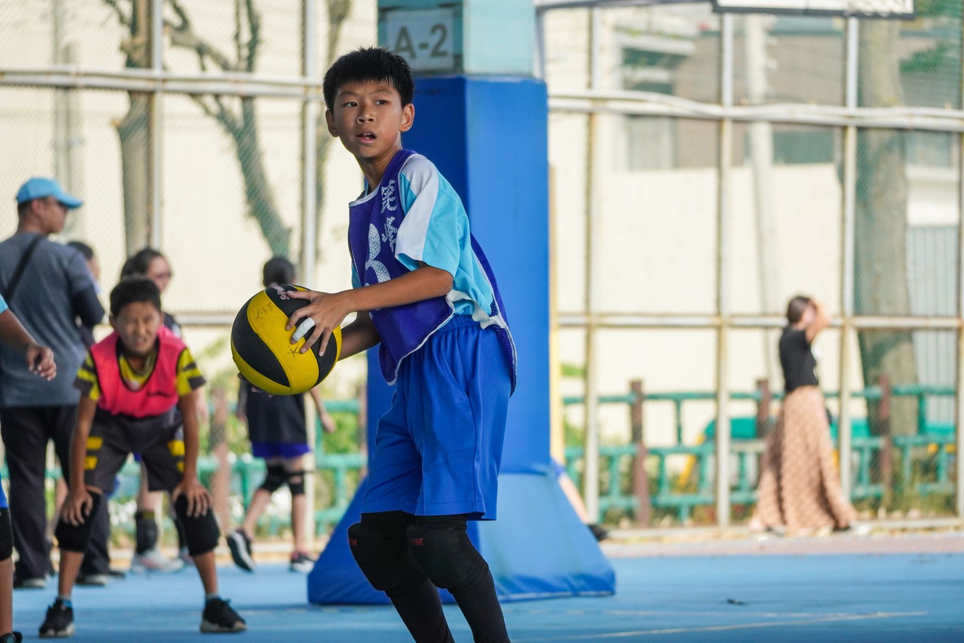 一個小男孩在籃球場上拿著一個籃球。