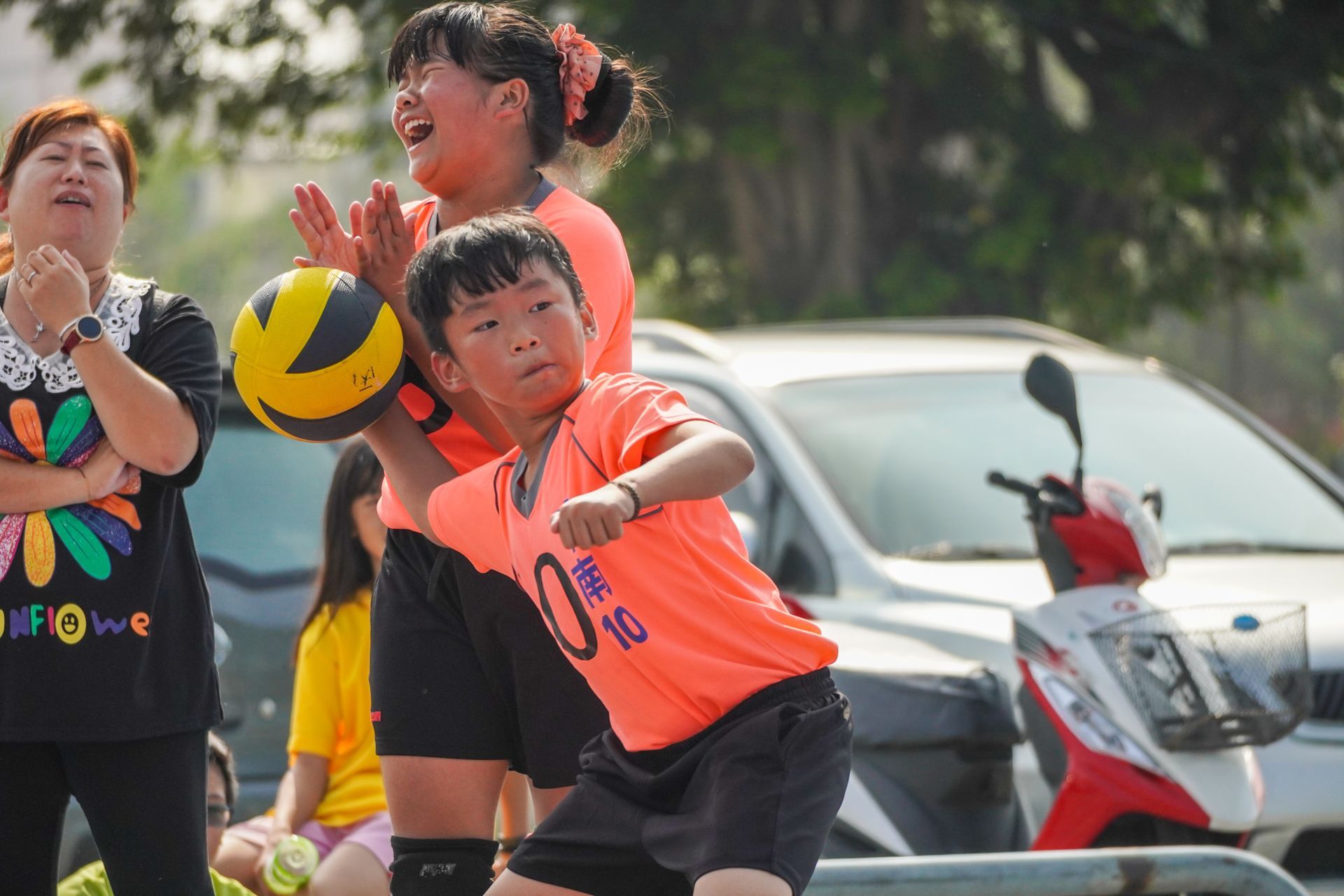 一個男孩和一個女孩正在停車場打排球。