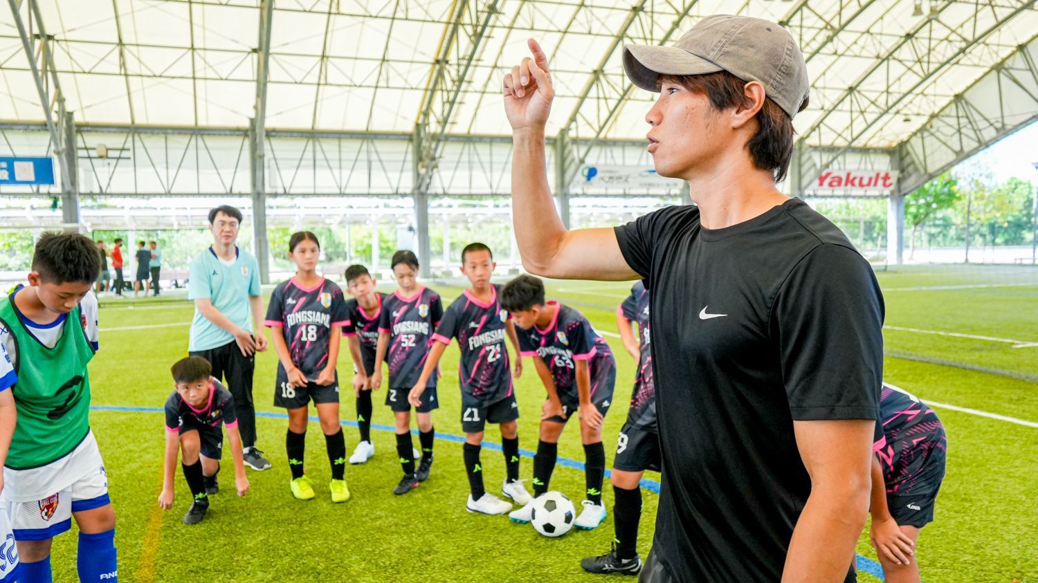 一個男人站在球場上一群足球員的前面。