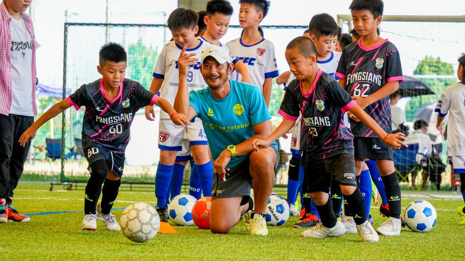 一群小男孩正在球場上和教練一起踢足球。