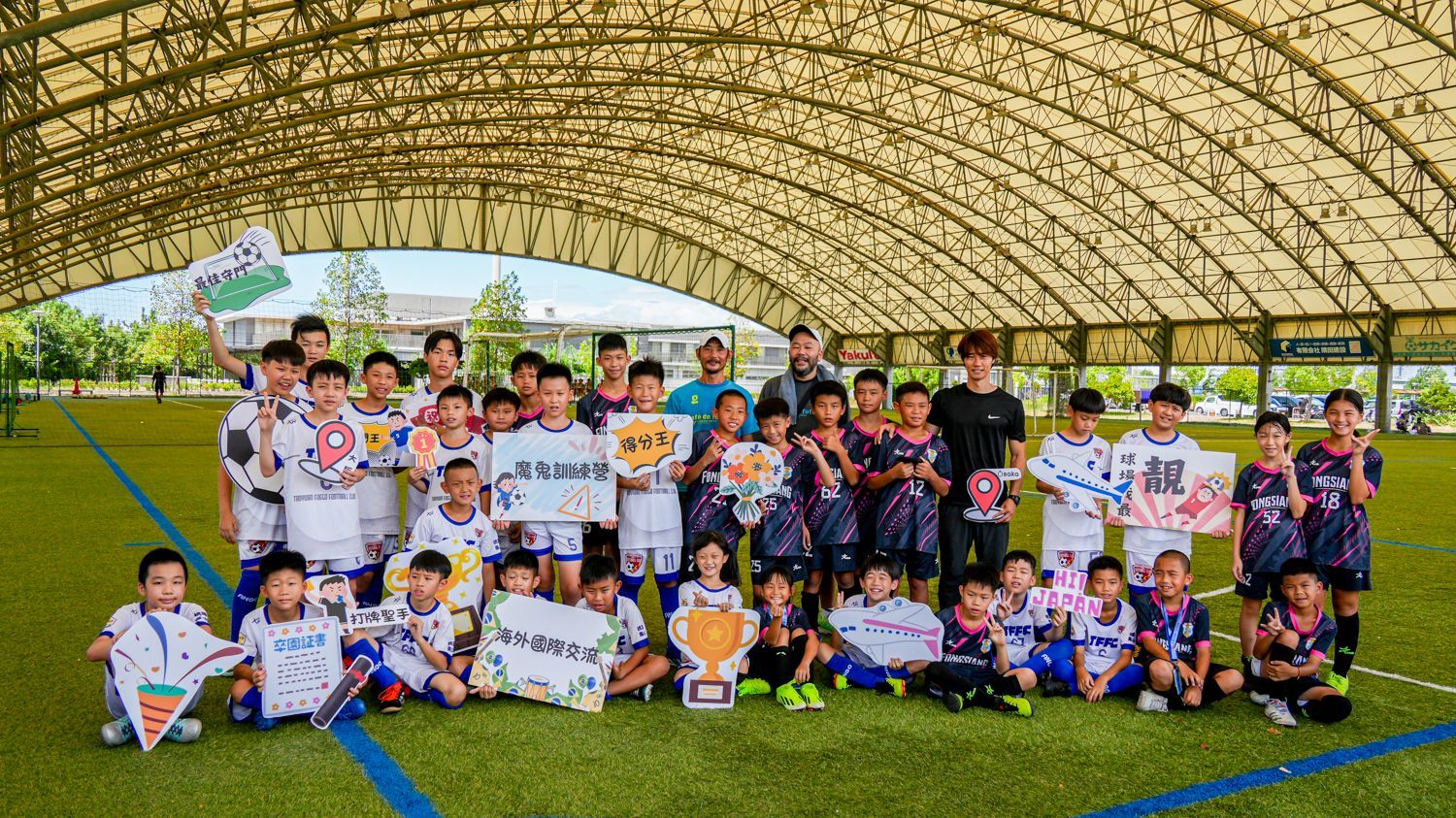 一群小男孩正在足球場上擺姿勢拍照。