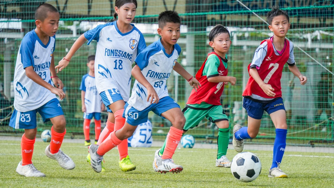 一群小男孩正在操場上踢足球。