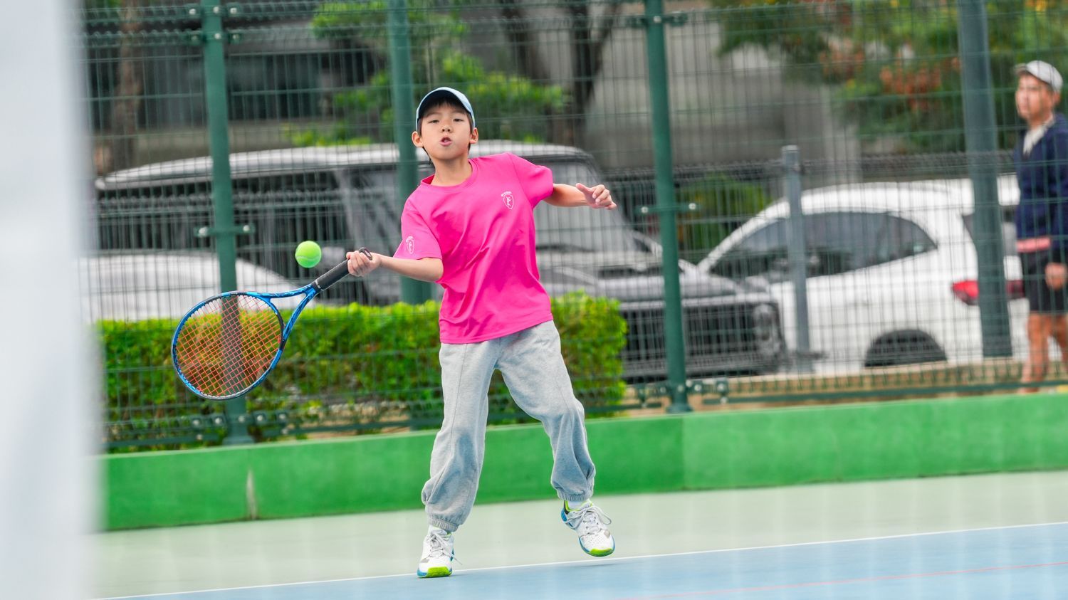 一個小男孩正在球場上打羽球。