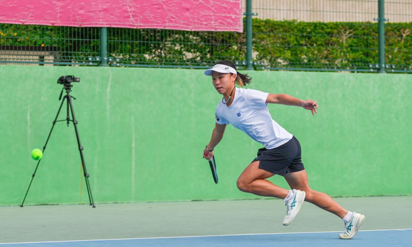 一名女子正在網球場上奔跑擊打網球。