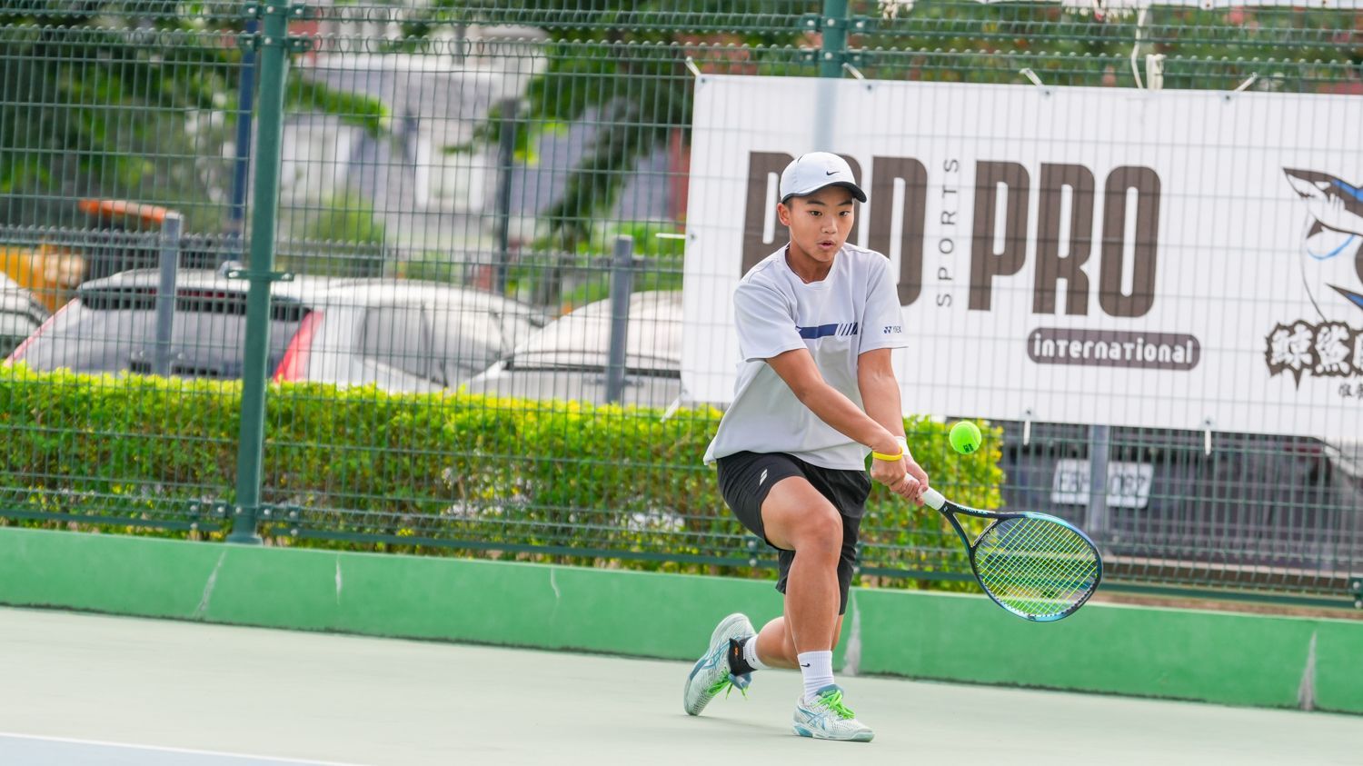 一個年輕人正在網球場上打網球。