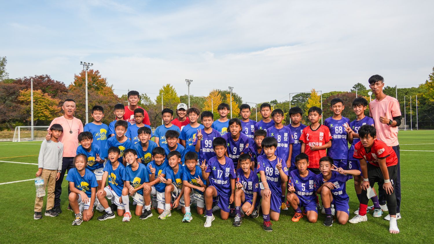 一群小男孩正在足球場上擺姿勢拍照。