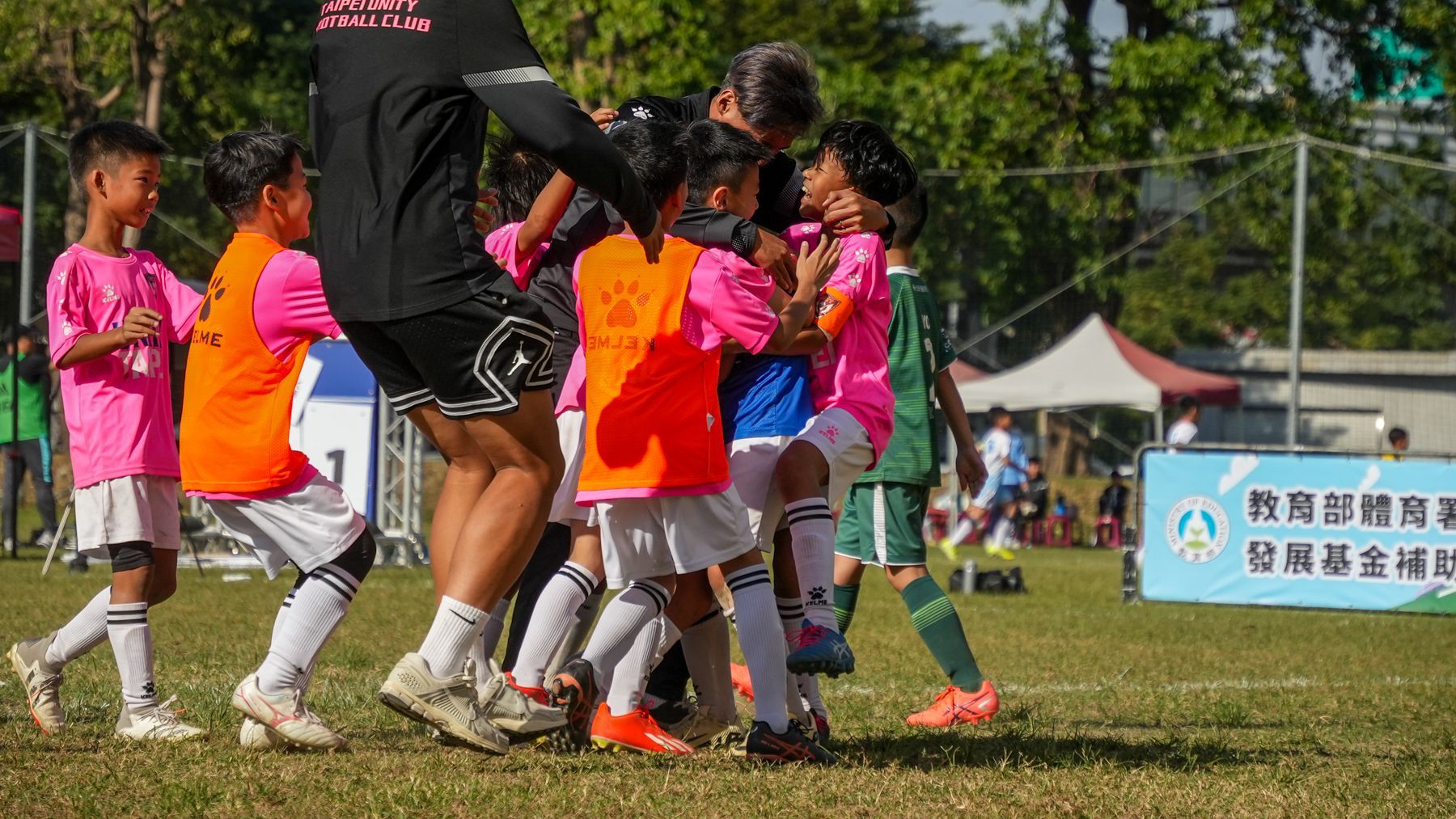 一群孩子正在操場上踢足球。