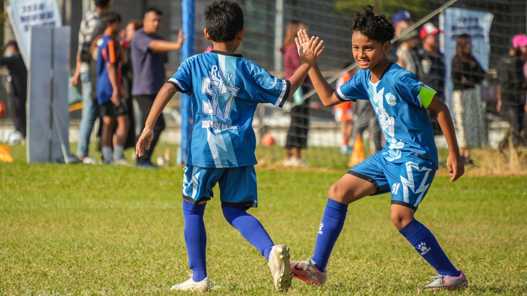 兩個小男孩在足球場上互相擊掌。