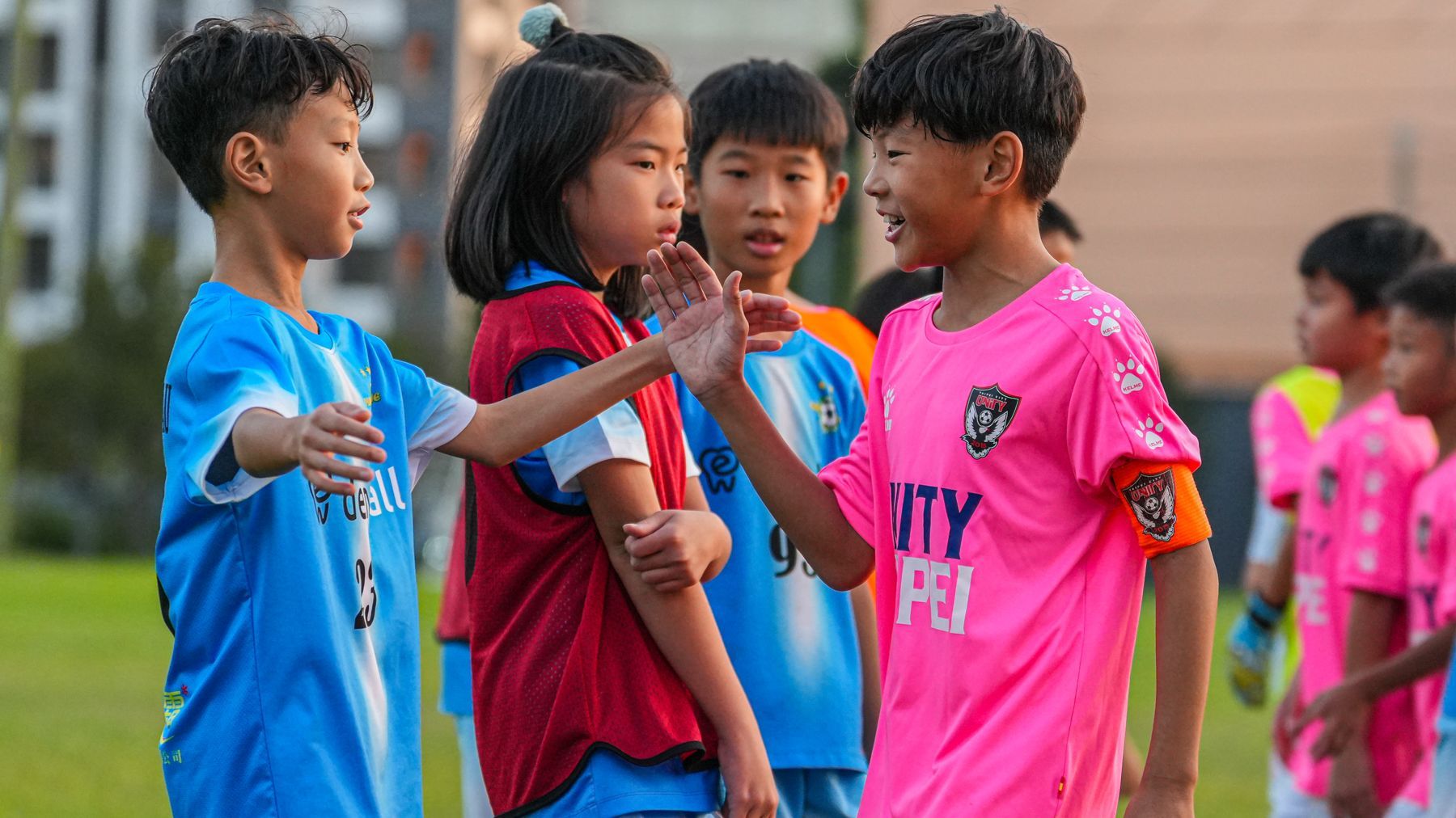 一群小孩在足球場上並排站立。