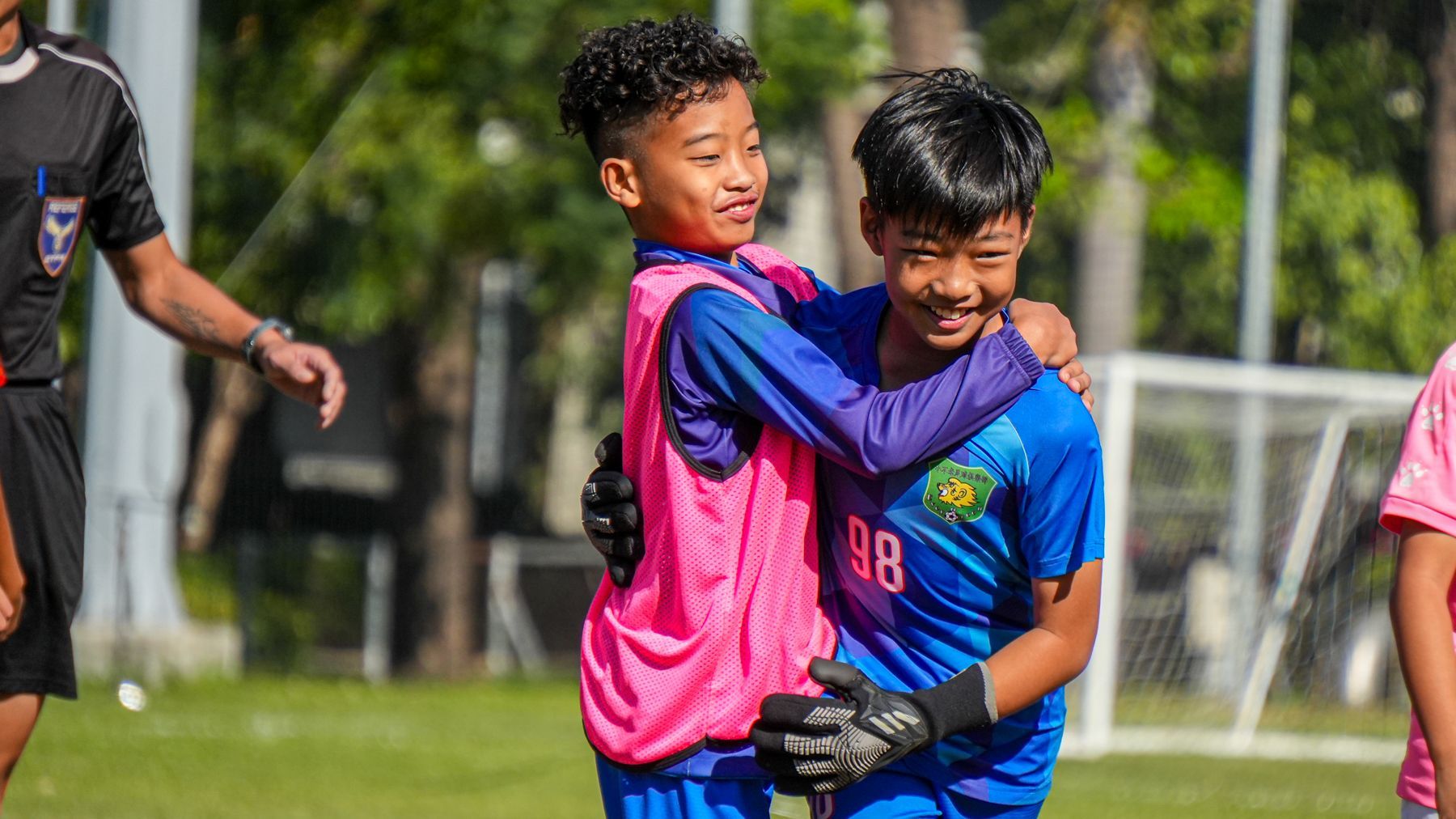 兩個小男孩在足球場上互相擁抱。