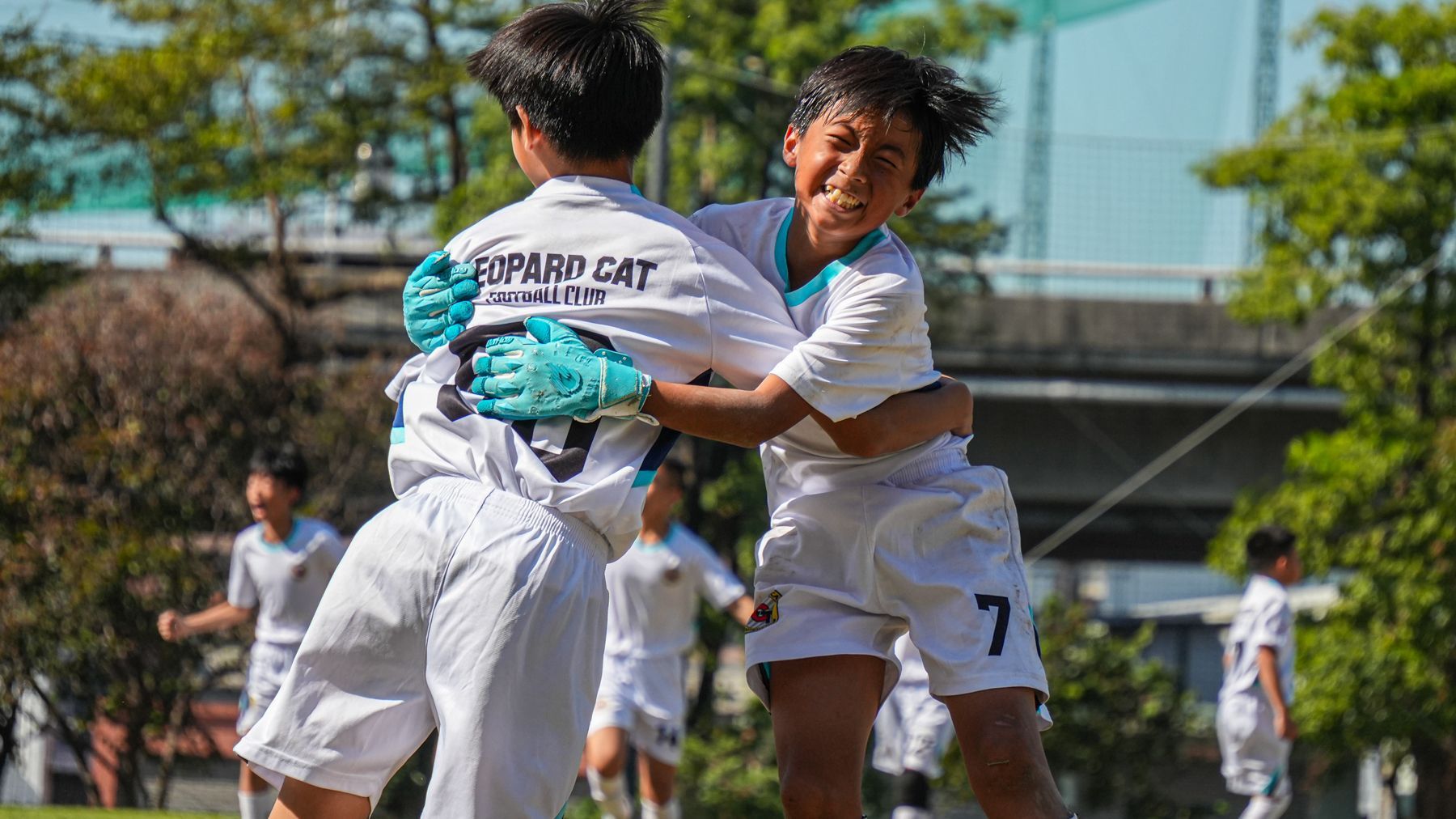 兩個小男孩在足球場上互相擁抱。