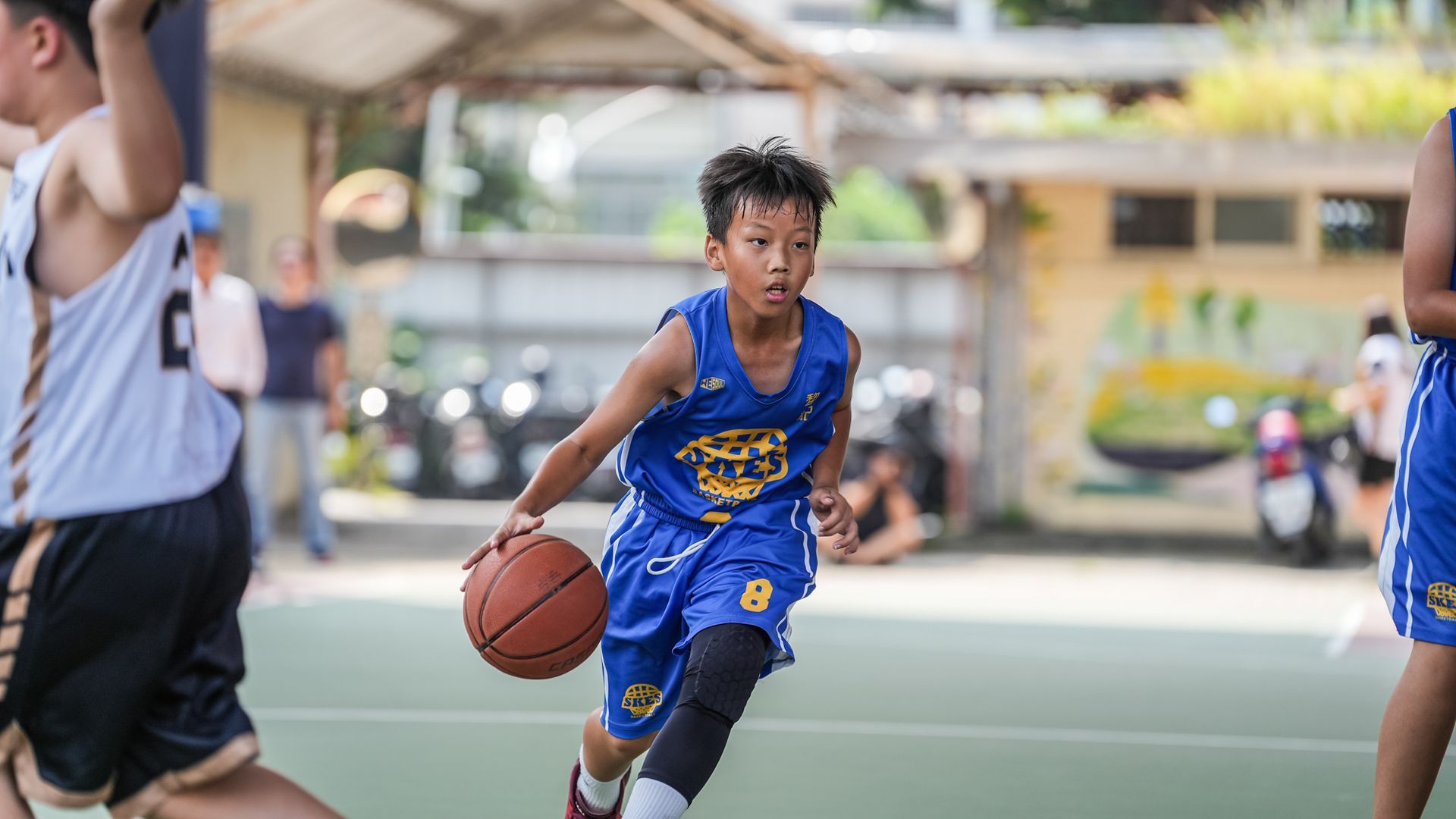 一個小男孩正在球場上打籃球。