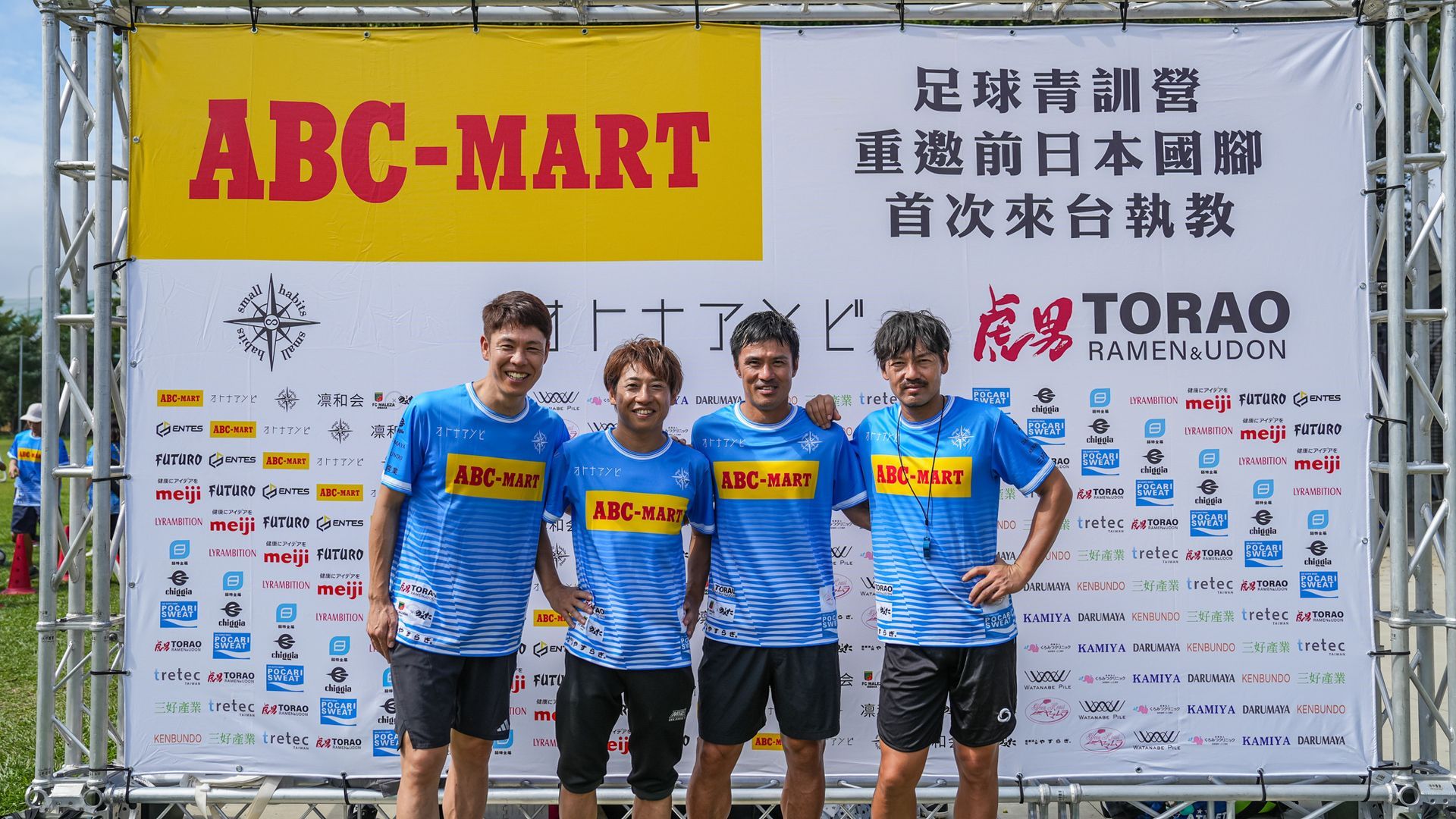 一群足球員在 abc-mart 的牌子前擺姿勢拍照